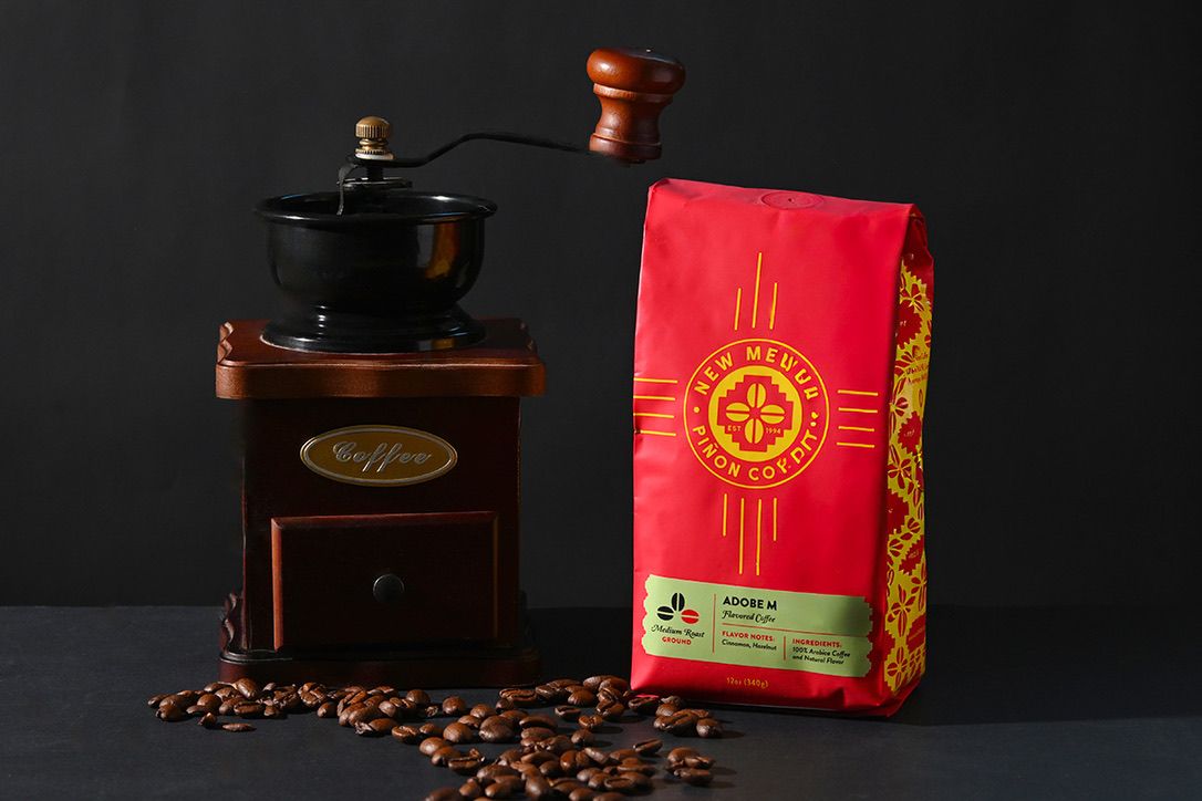 Coffee grinder and red coffee bag arranged in moody dark lighting.