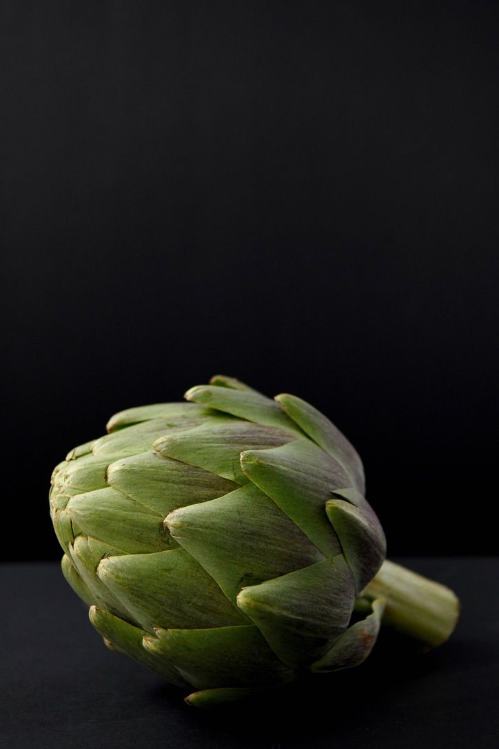 Fresh artichokes photographed from different angles against a black background.