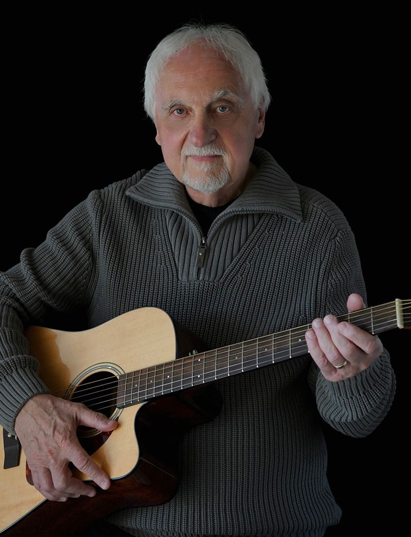 Series of shots showing a guitarist in a gray sweater performing against dark background.