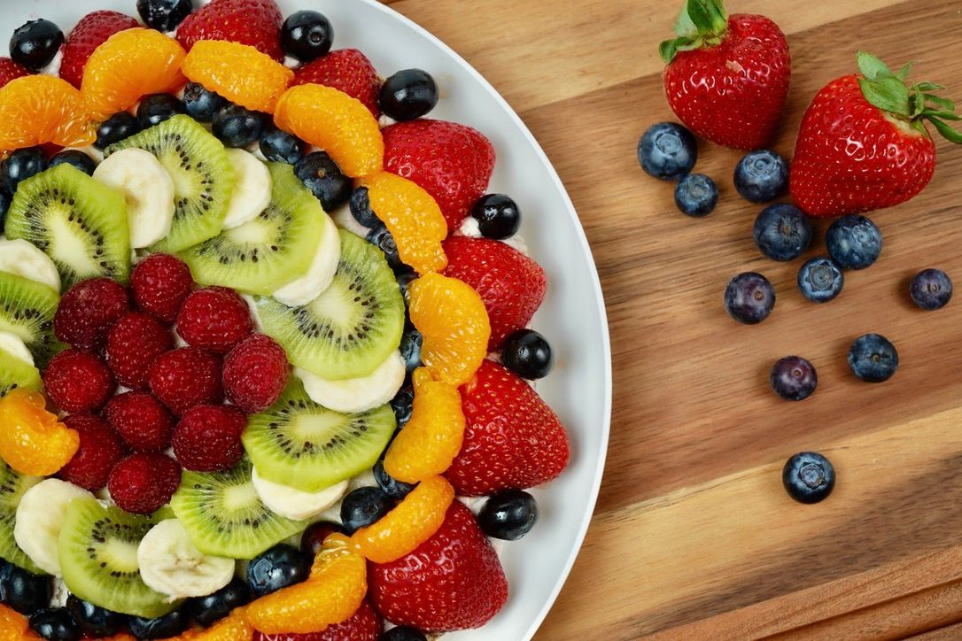 Colorful fruit tort with kiwi, berries, oranges and bananas arranged in a spiral pattern.