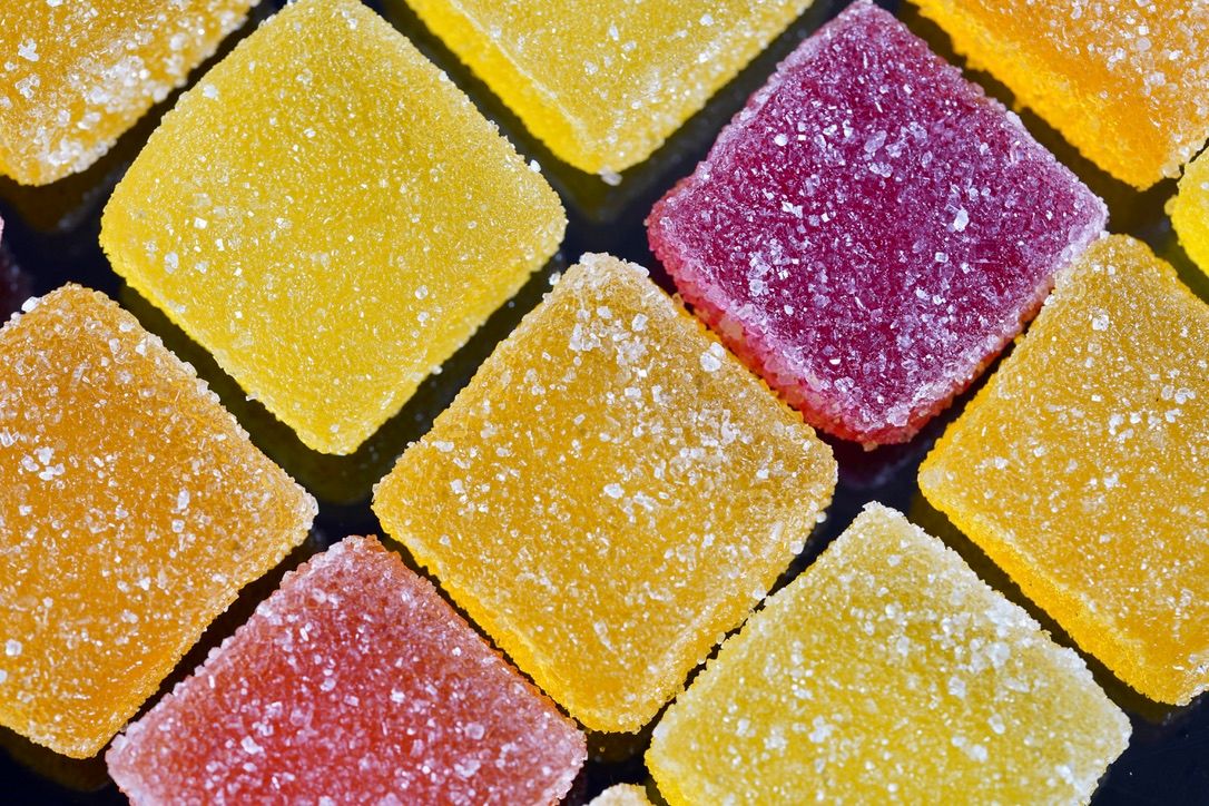 Colorful fruit jellies dusted with sugar in yellow and purple hues arranged in a grid pattern.