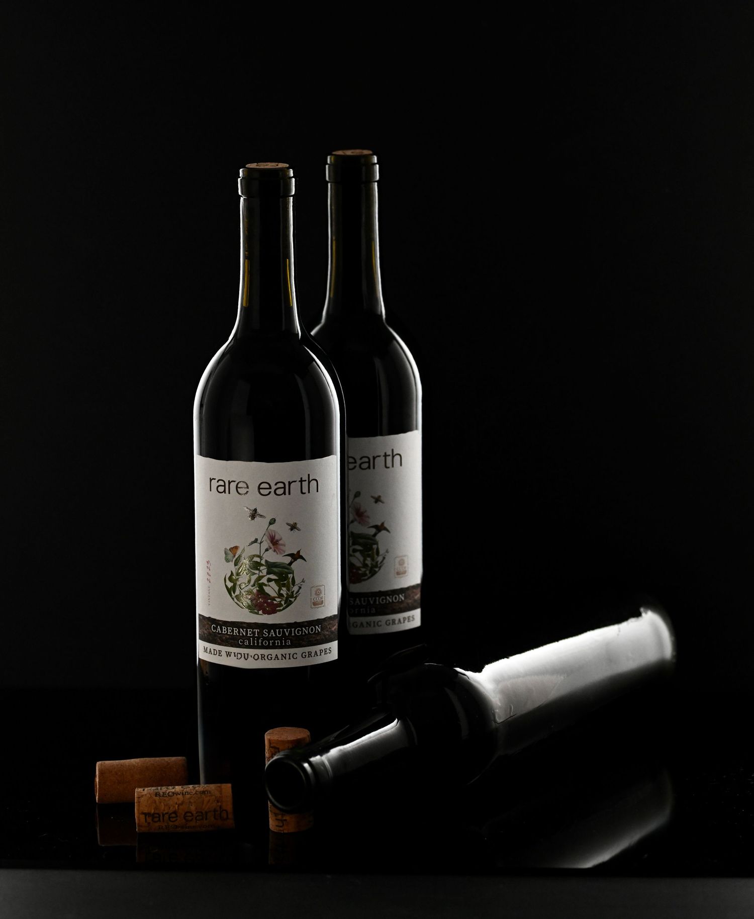 Dramatic low-key lighting on wine bottles and corks against black background in sequential composition.