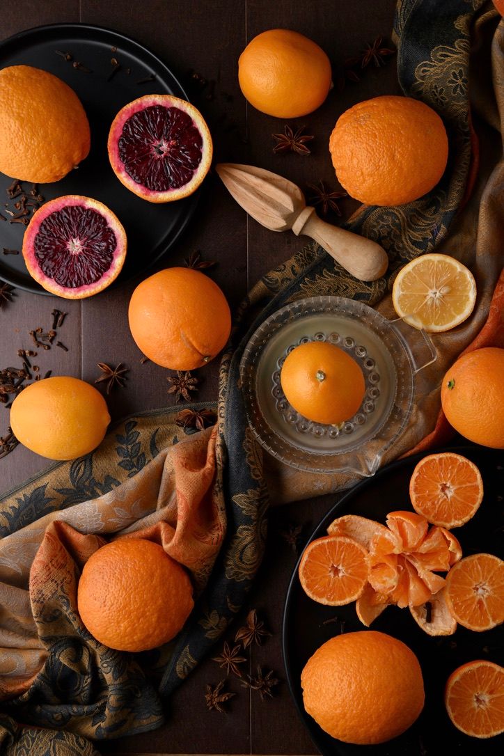 Fresh blood oranges and citrus fruits arranged with vintage props and star anise on dark rustic background.