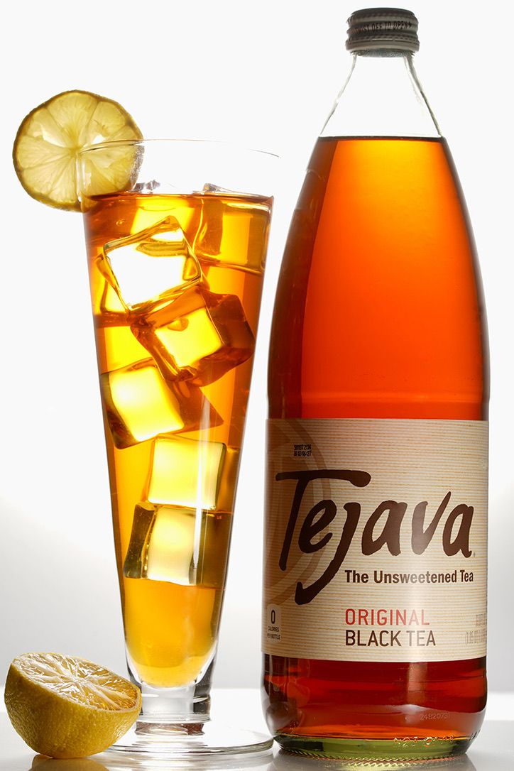 Bottles and glasses of iced tea with lemon slices and ice cubes on white background.