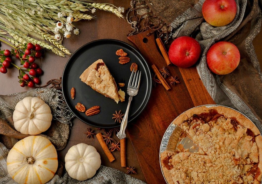Autumn pie scene with pumpkins, apples and rustic decor on wooden table.