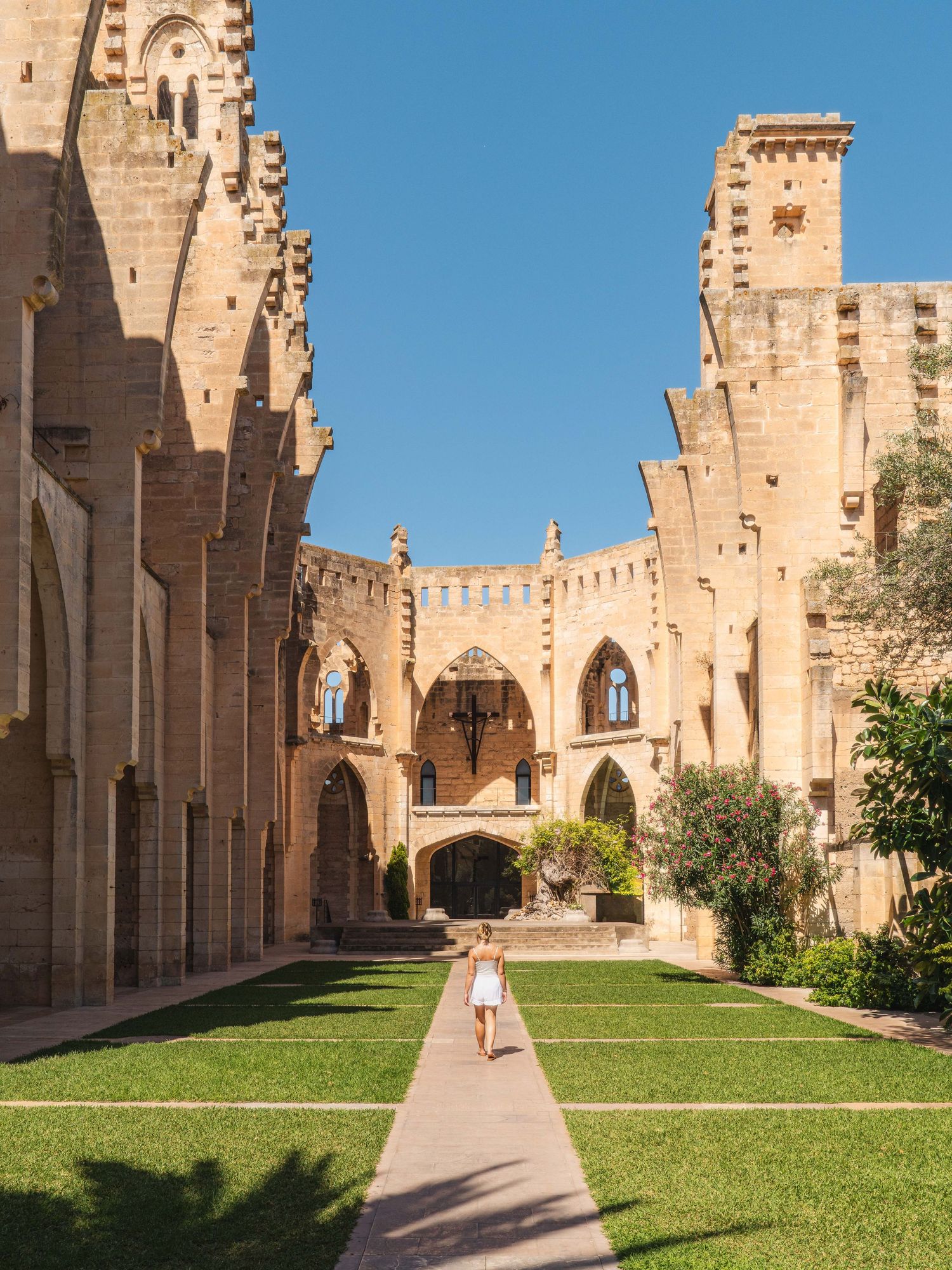 Historic stone cathedral courtyard with manicured lawn and gothic architecture.