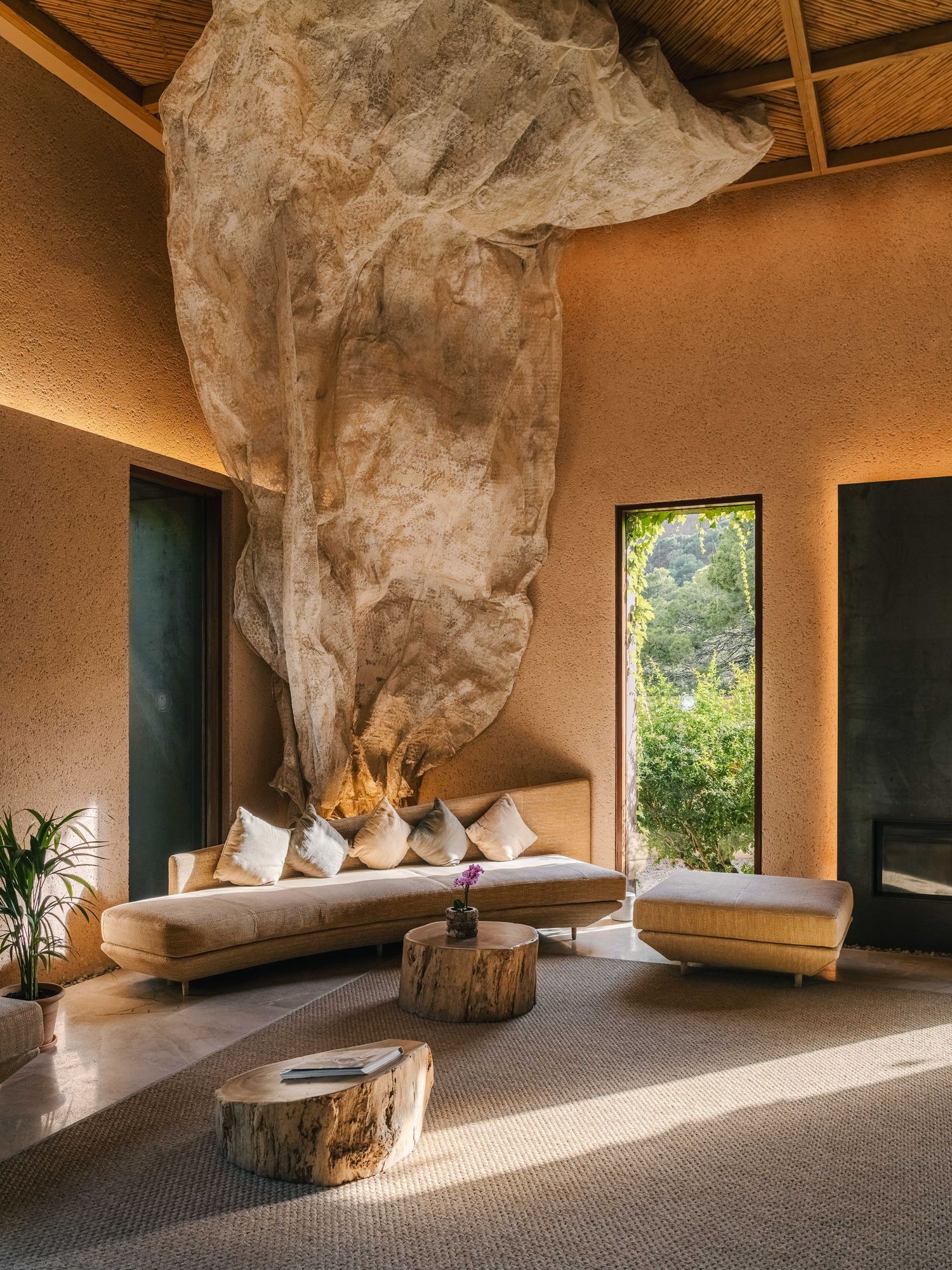 Modern cave-like interior with natural stone walls and large windows overlooking nature.