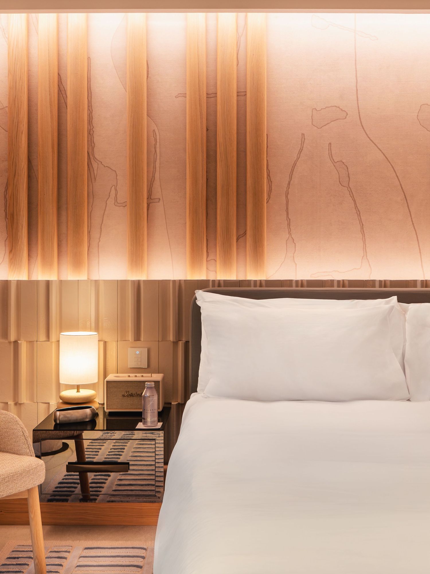 Modern hotel room interior with white bedding and warm ambient lighting.