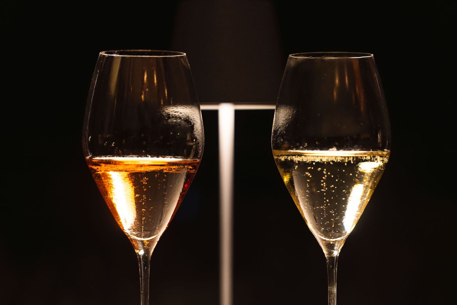 Two glasses of sparkling champagne or prosecco with bubbles against a dark background.