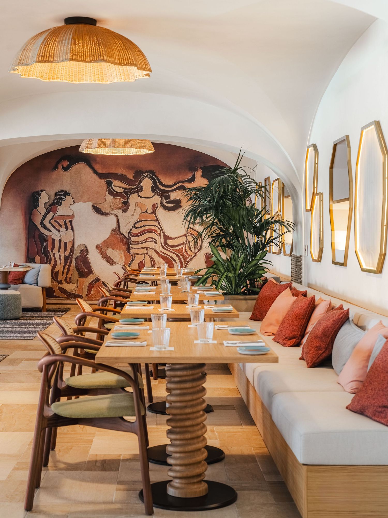 Modern restaurant interior with white walls, curved seating, and rattan pendant lights creating a warm ambiance.