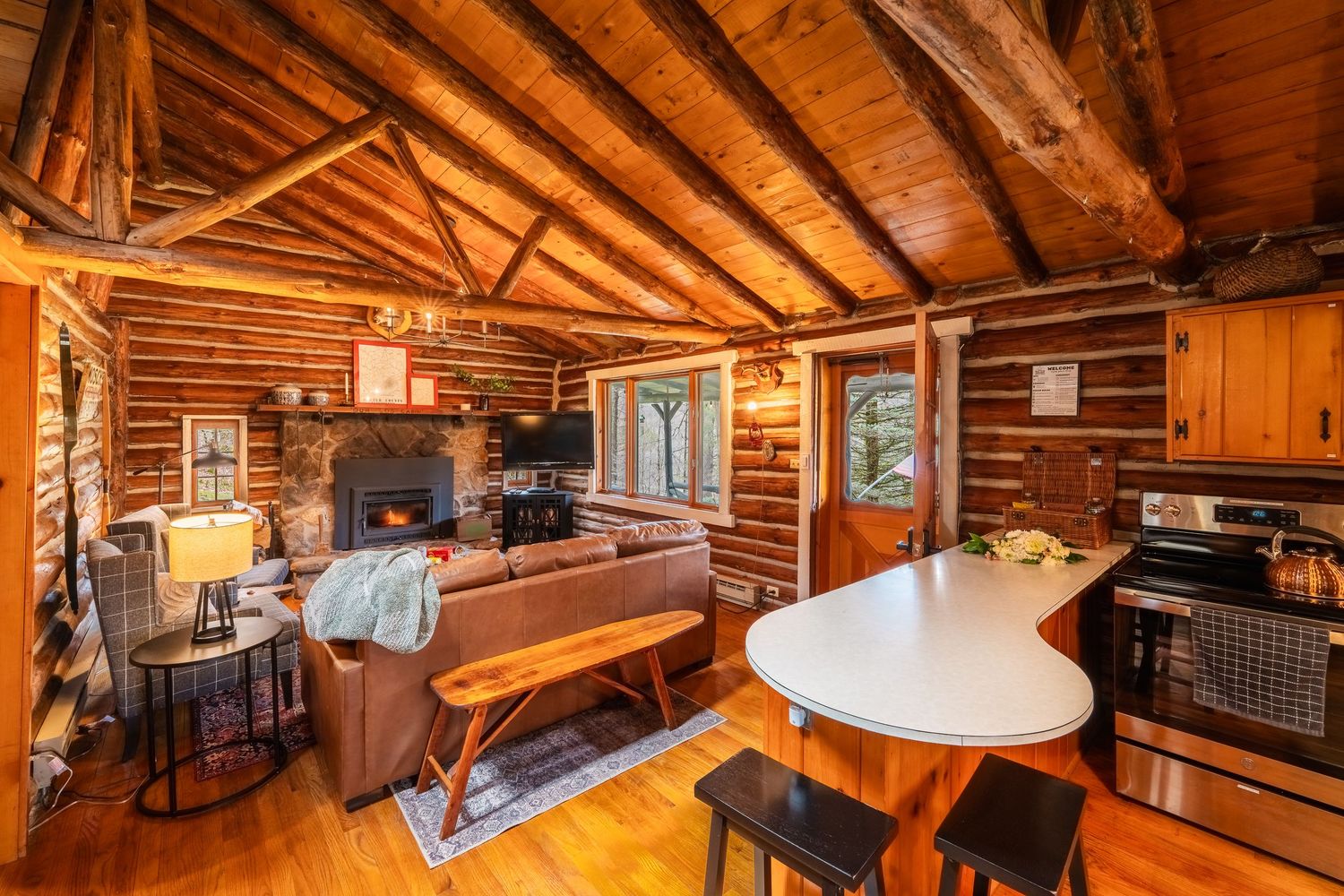 Cozy rustic log cabin interior with exposed wooden beams, loft space, and warm lighting creating a welcoming atmosphere.