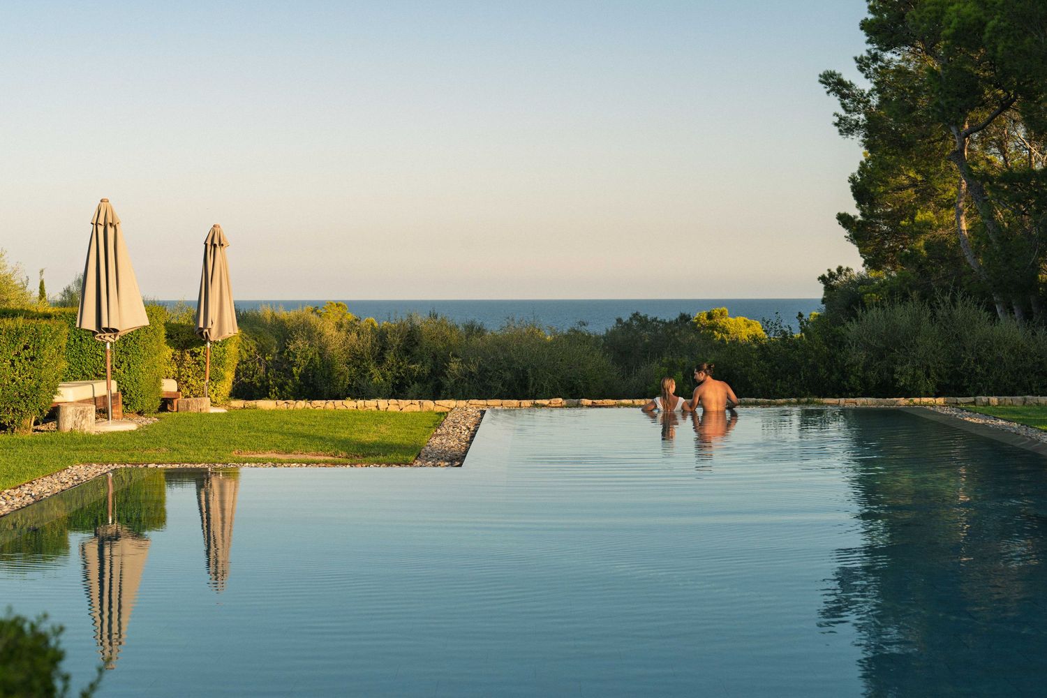Serene infinity pool overlooking a scenic coastal landscape at sunset.