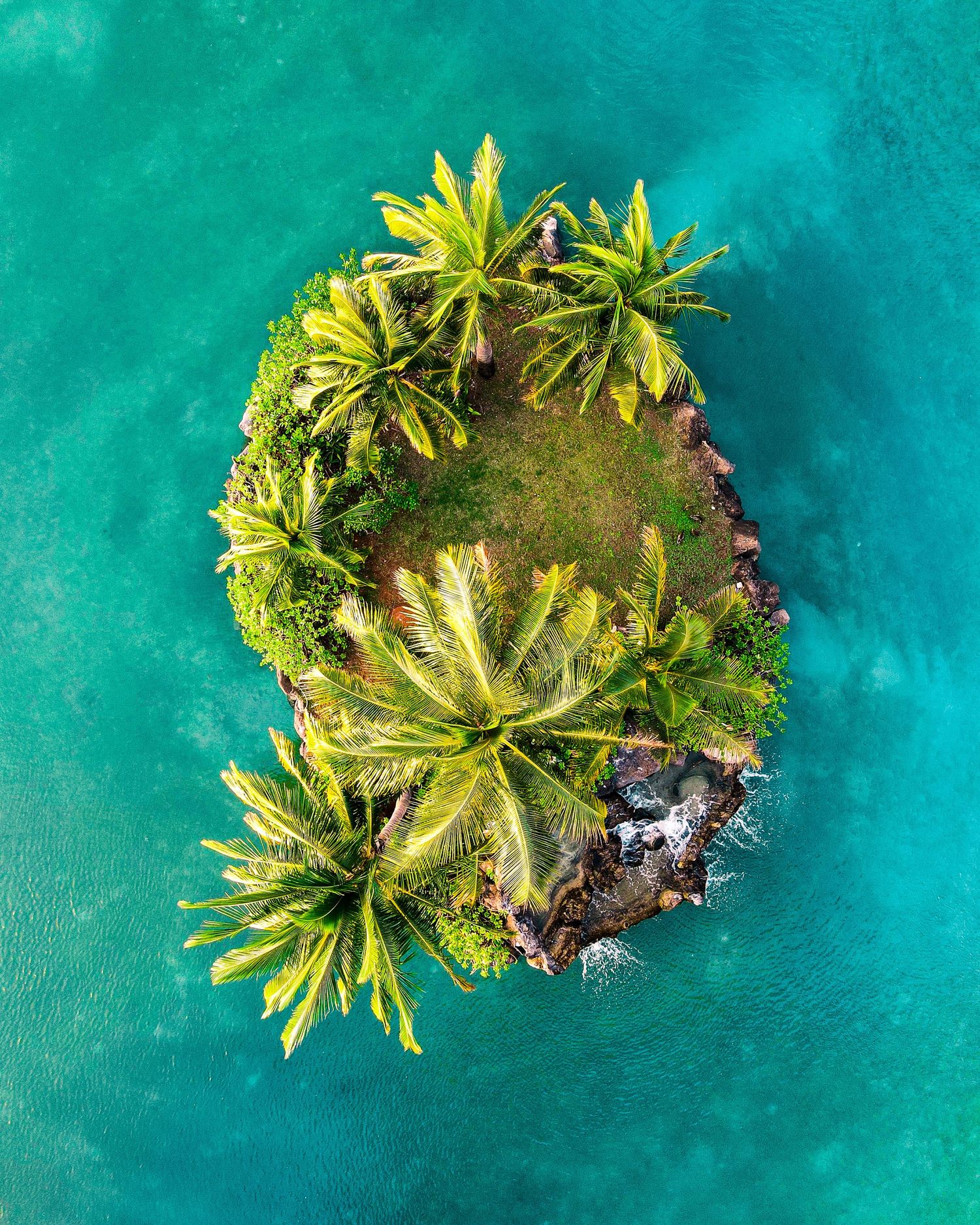 Aerial view of small tropical islands with palm trees surrounded by turquoise waters.