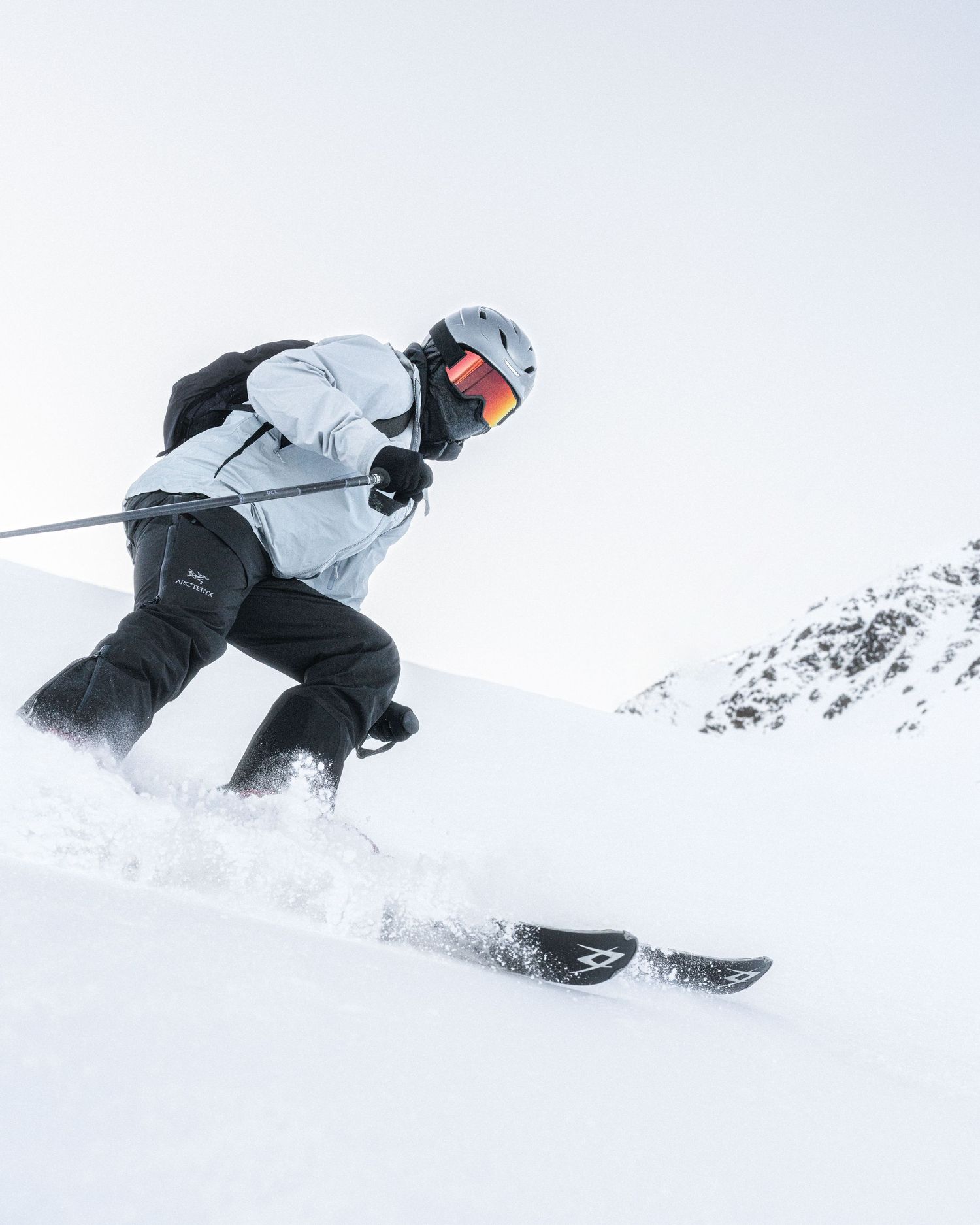 Dynamic sequence of a skier carving through fresh powder snow on a steep mountain slope.