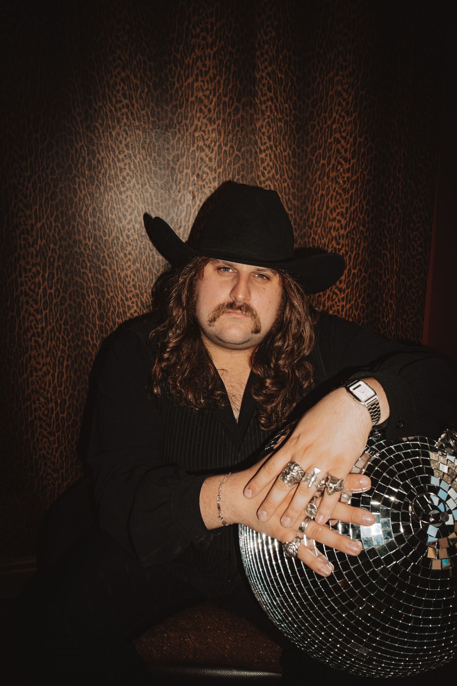 Dark portraits featuring cowboy hat and disco ball against textured background.