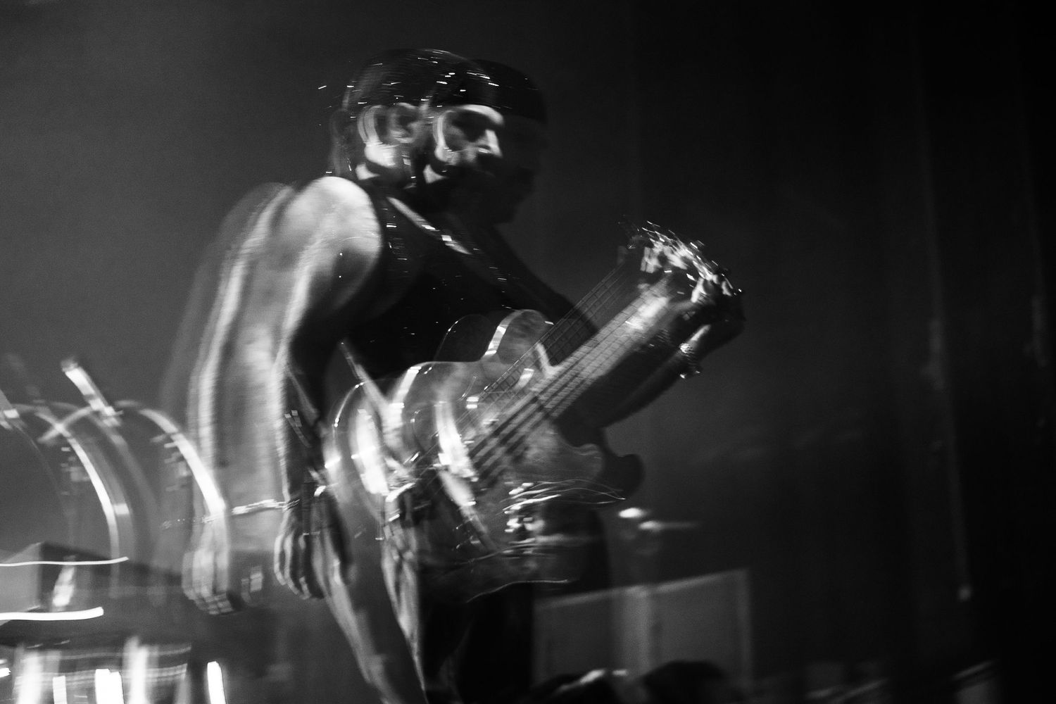 Dramatic black and white photo of musician playing guitar on dimly lit stage.
