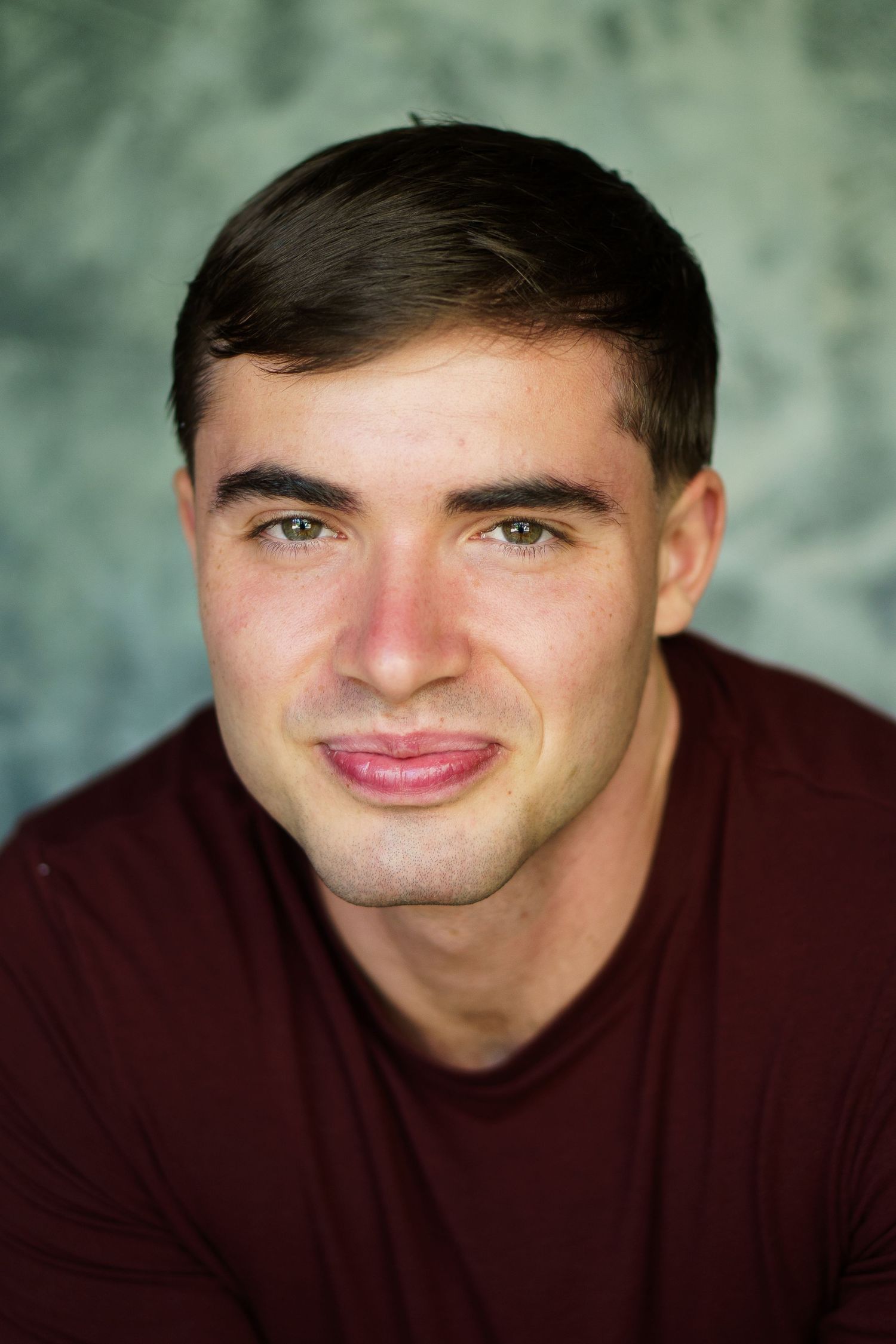 A series of headshots showing a person in a burgundy sweater making playful expressions against a textured background.