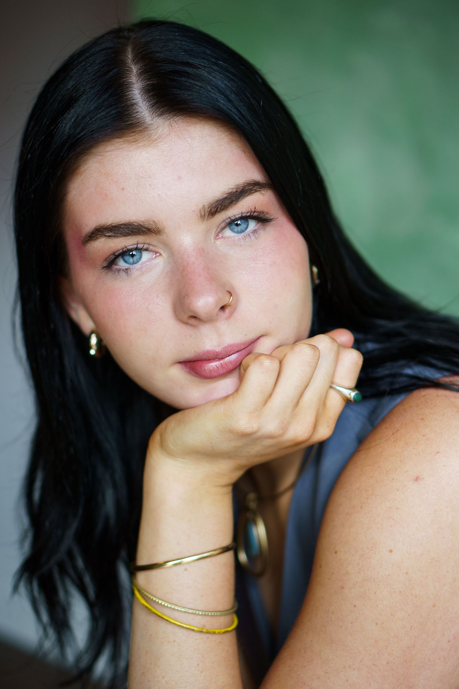 Portrait series showing close-up shots with dark hair and blue eyes against a blurred green background.