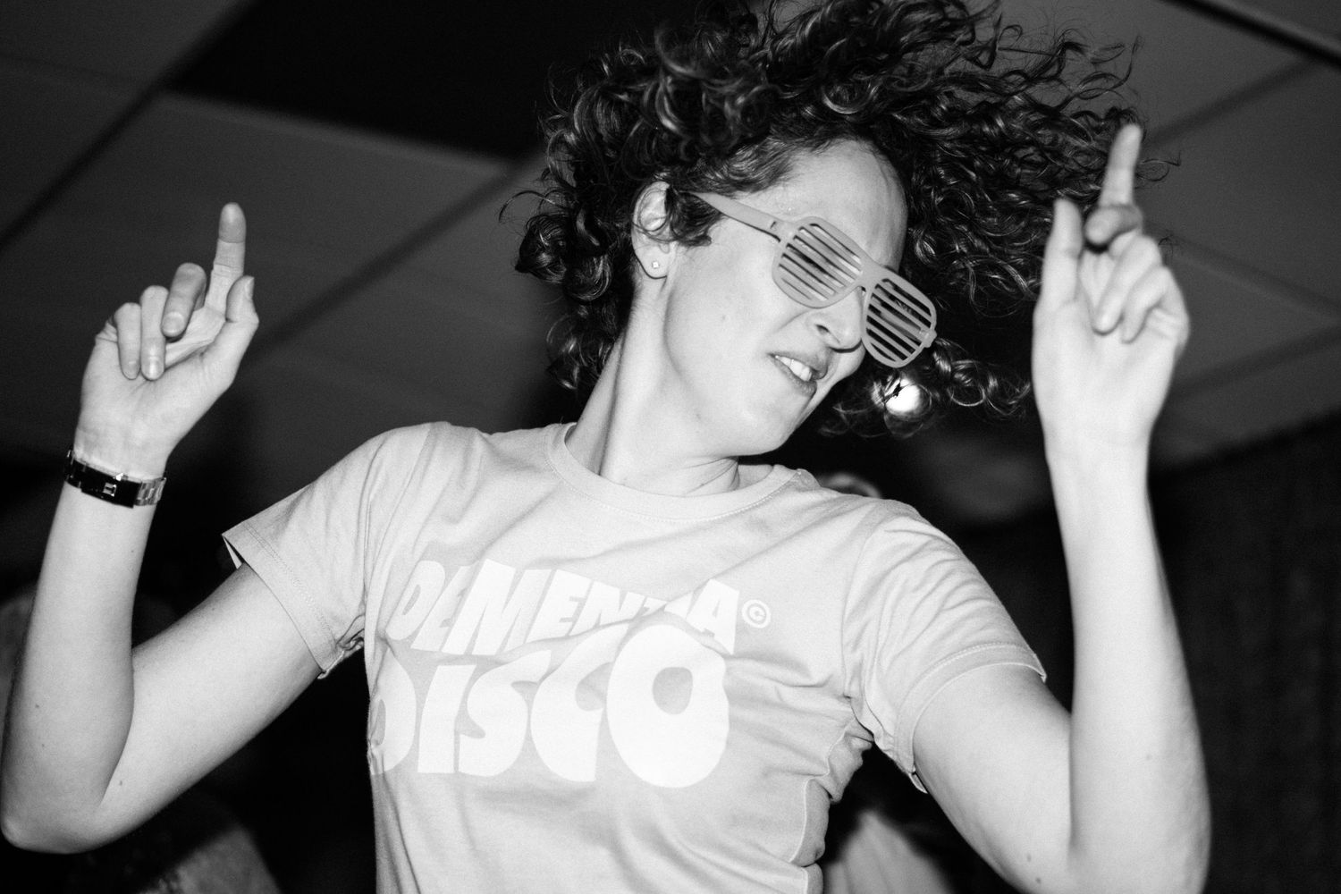 Black and white photos showing people dancing and having fun at a party with their hands in the air.