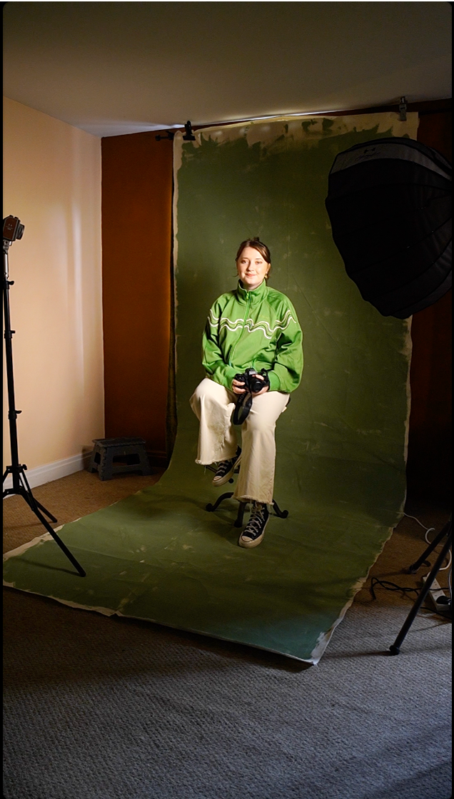 A behind-the-scenes photo shoot setup with green backdrop and studio lighting equipment.