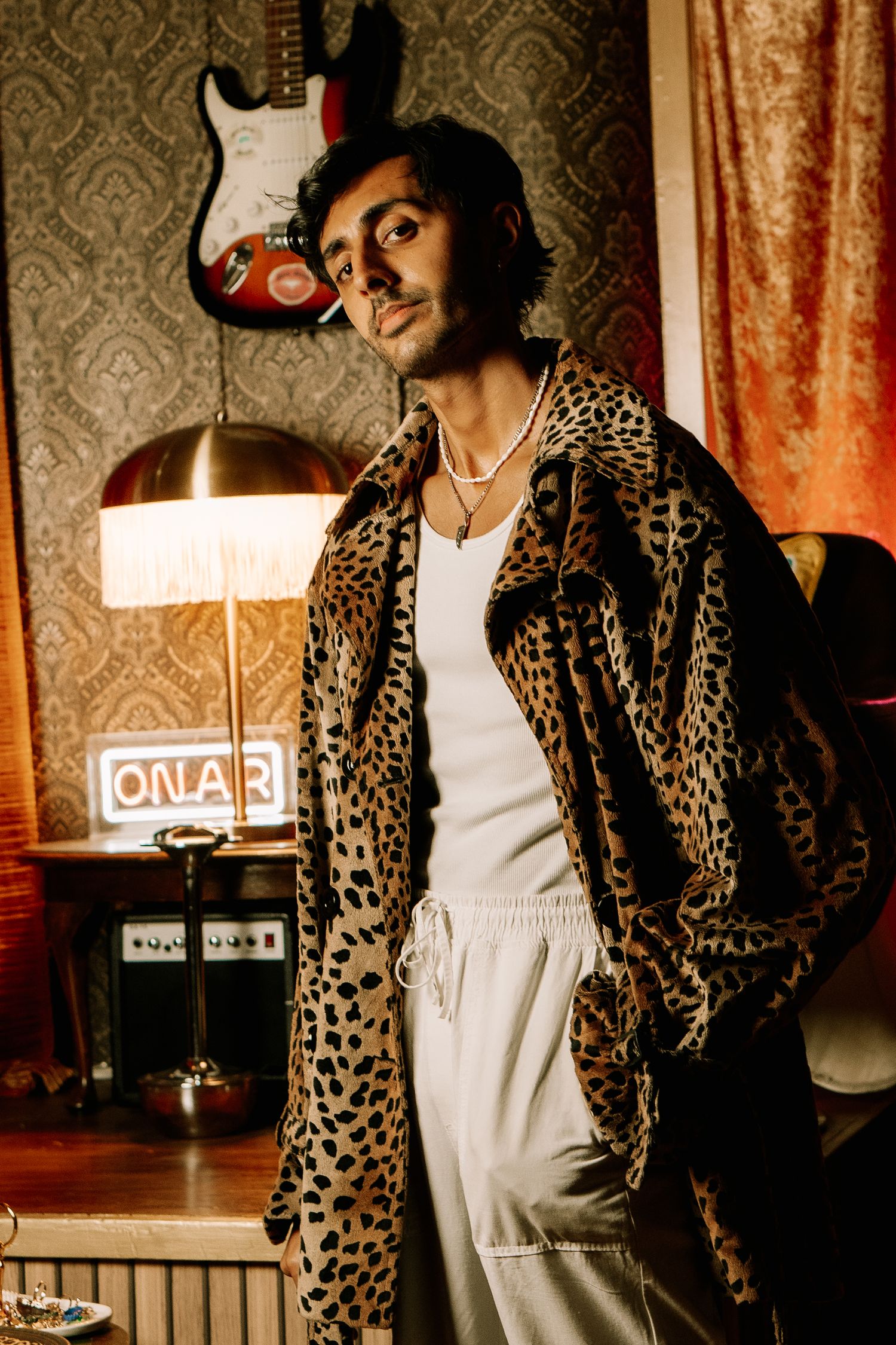 A stylish scene with leopard print coat and electric guitar against vintage wallpaper.