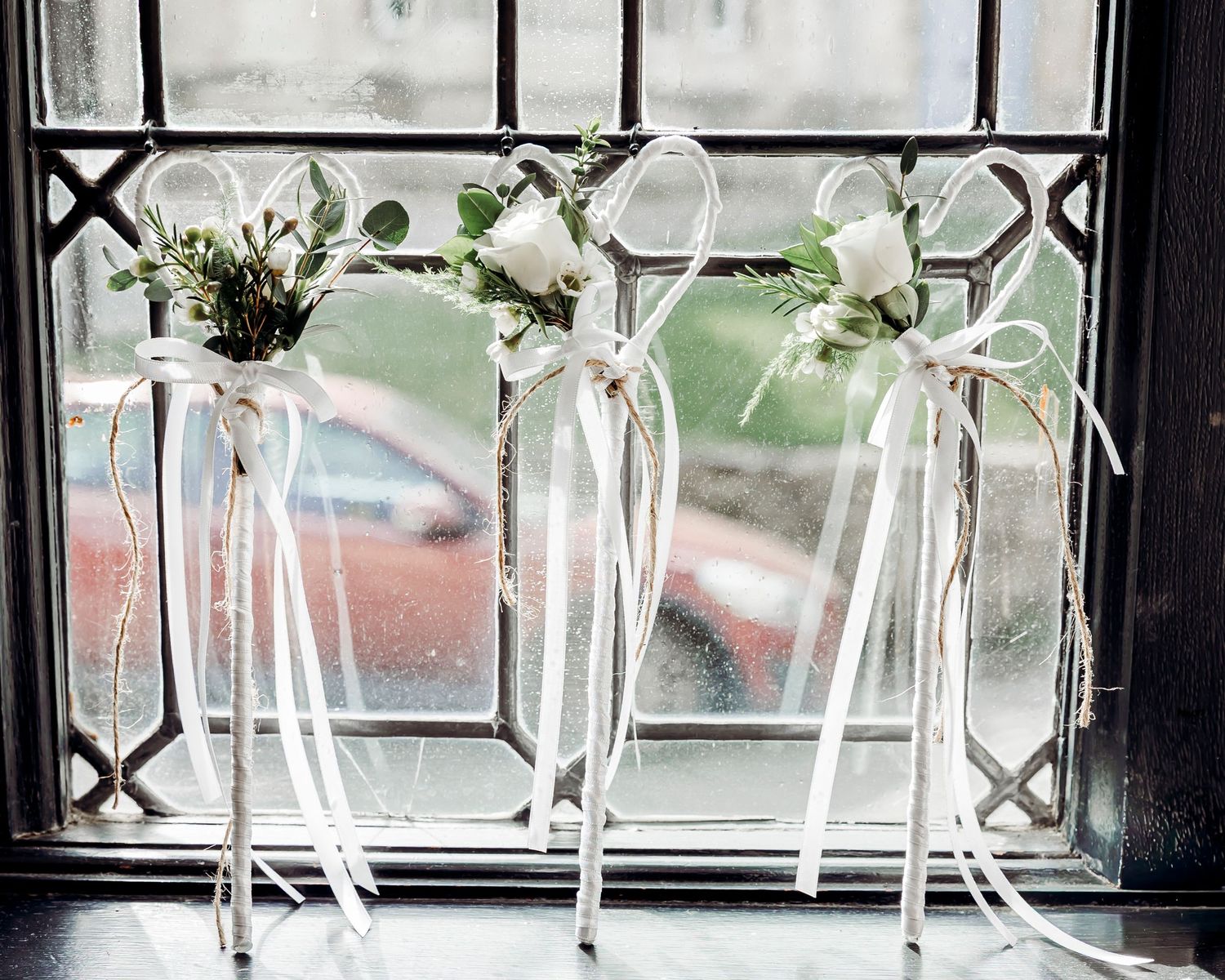 Elegant white floral wedding decorations with ribbon streamers displayed on a window ledge.