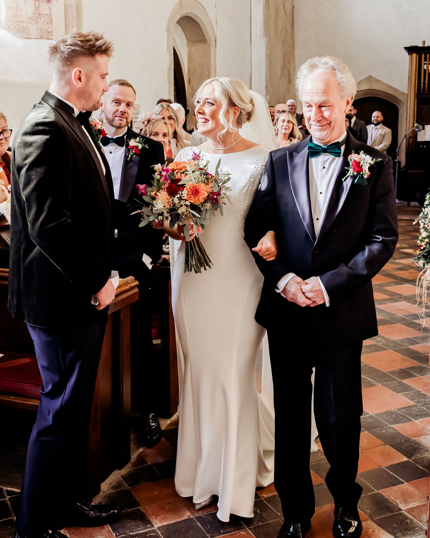 Bride smiling joyfully as she meets groom at altar with father beside her in church ceremony.