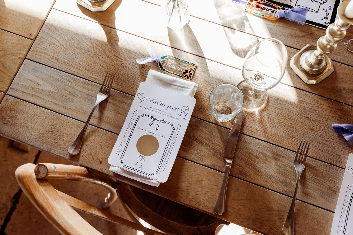 Overhead view of rustic wooden wedding table setting with silverware, glassware, and folded menu card.