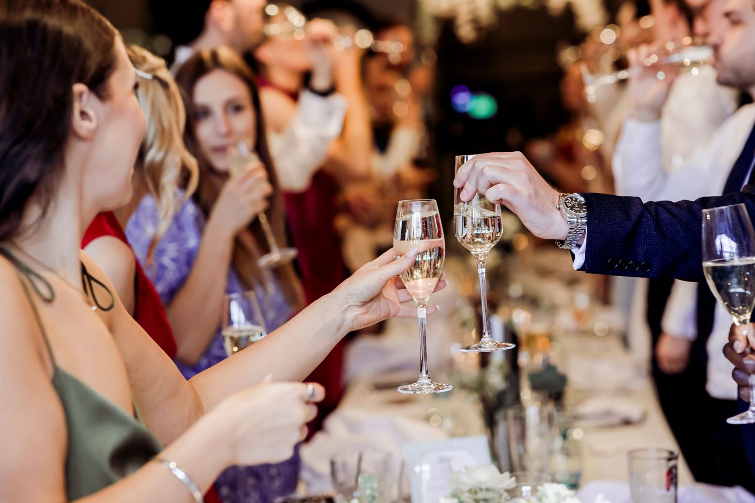 Wedding guests raising champagne glasses in a celebratory toast at reception.