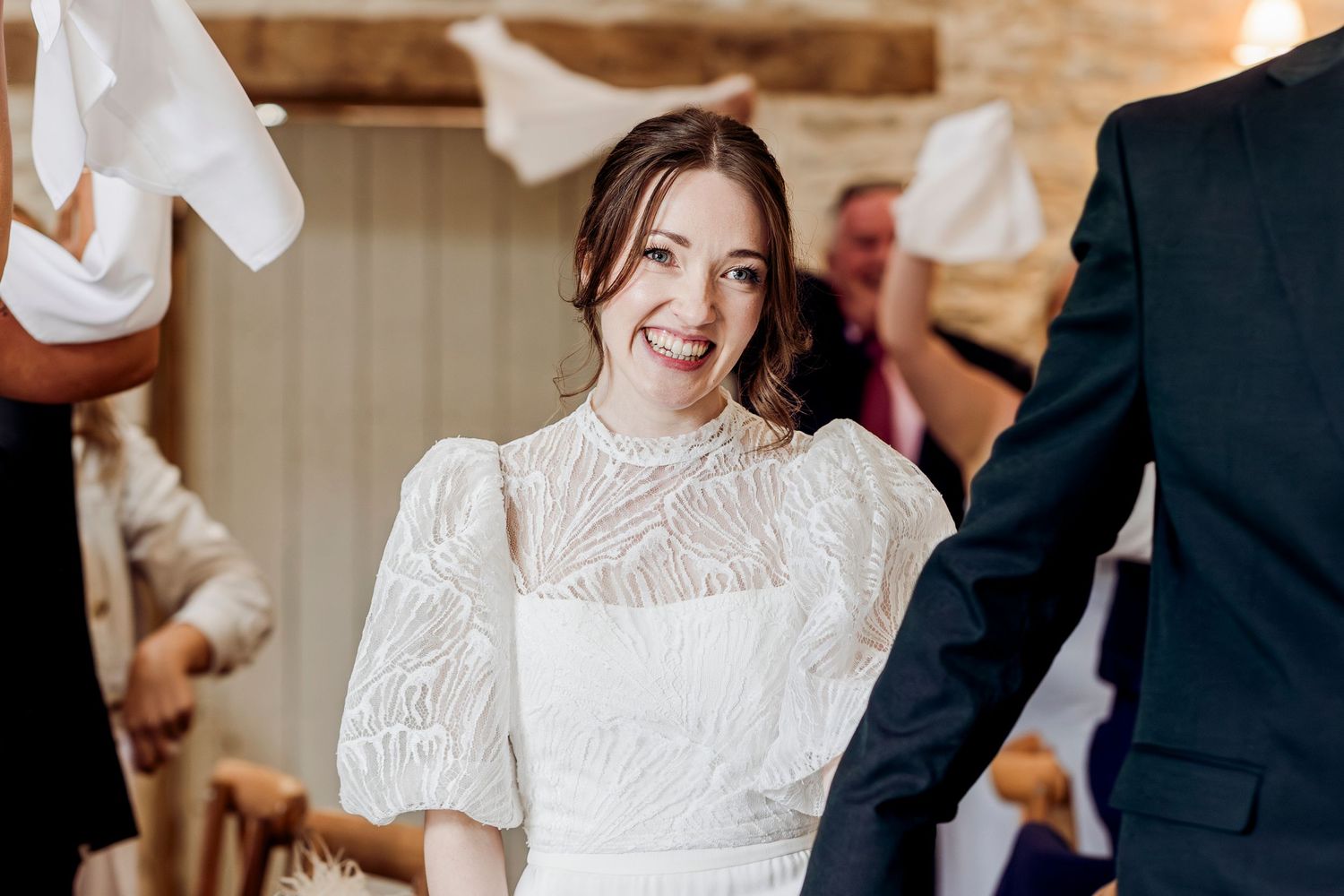 Smiling bride in white lace high-neck puff sleeve wedding dress during ceremony.