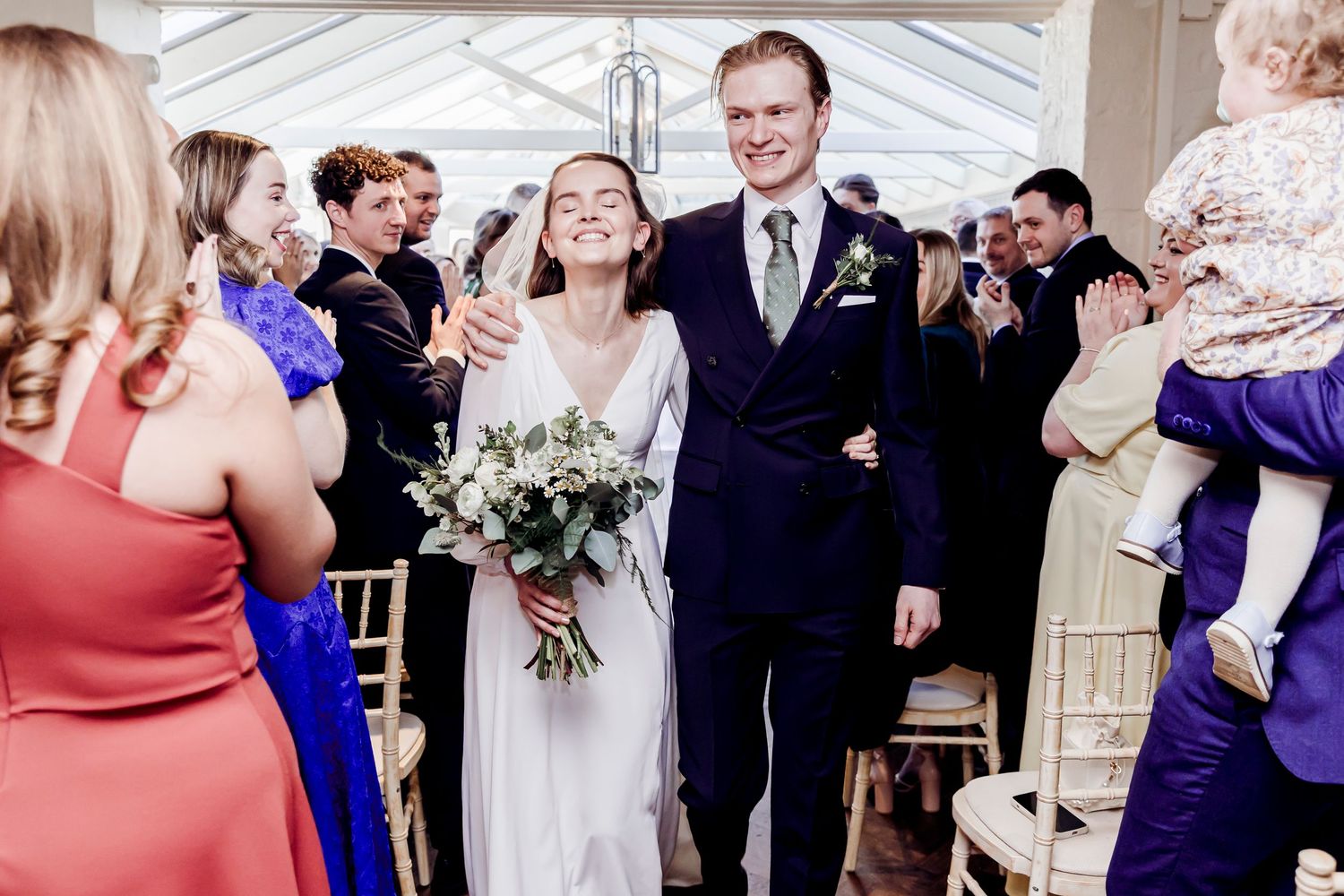 Happy newlyweds walk down aisle together as guests celebrate their wedding ceremony.