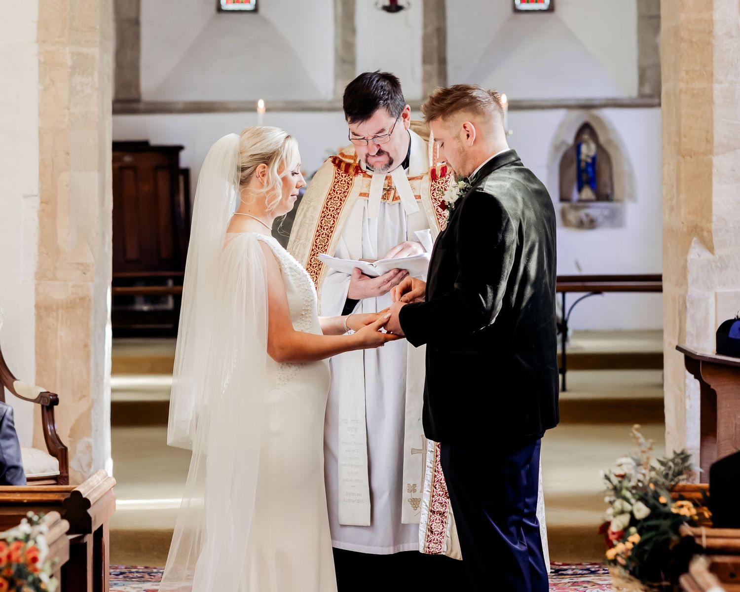 Bride and groom exchanging vows at the altar with a priest during a church wedding ceremony.