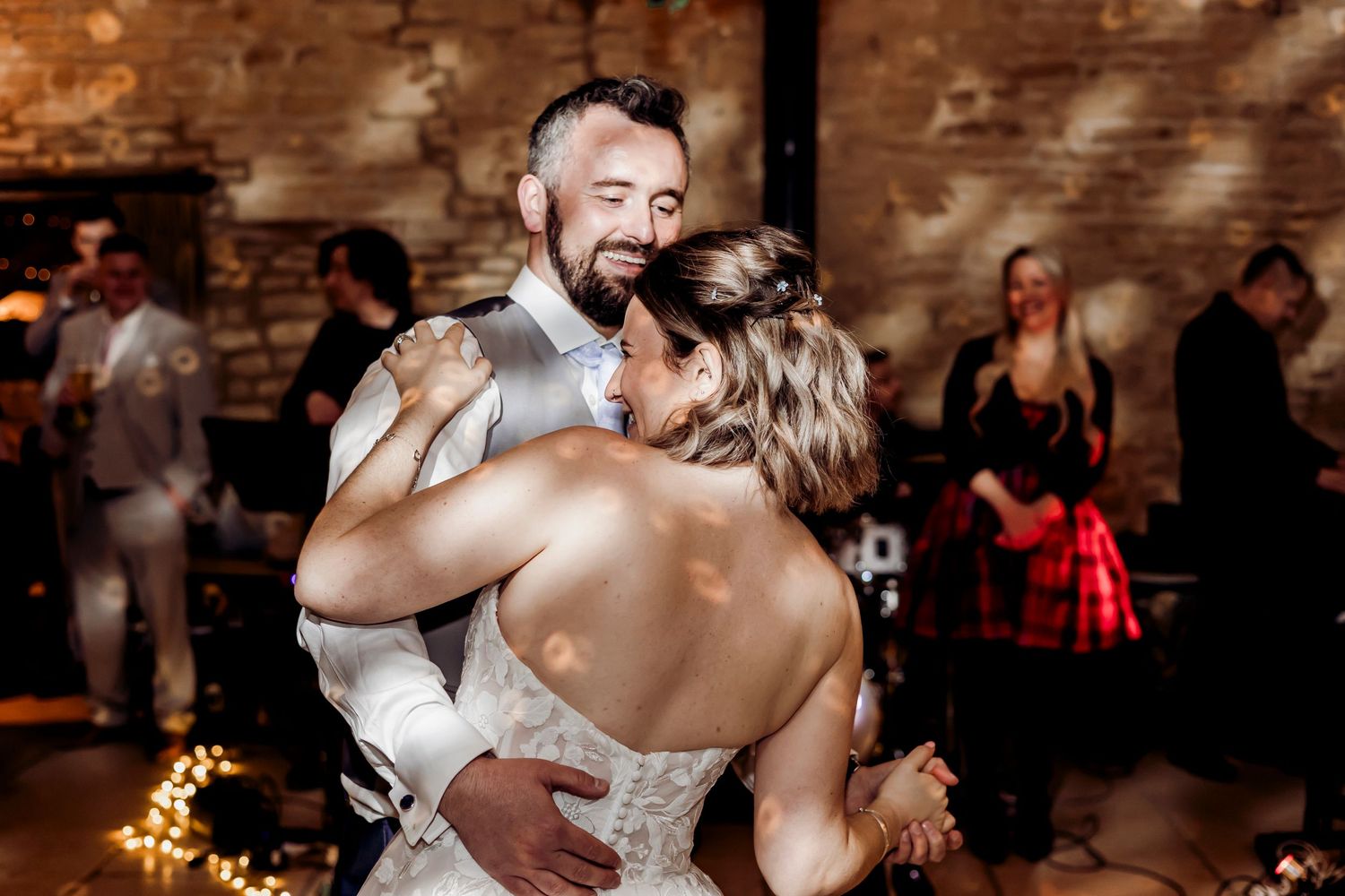 Groom smiling joyfully while embracing bride during first dance at wedding reception.