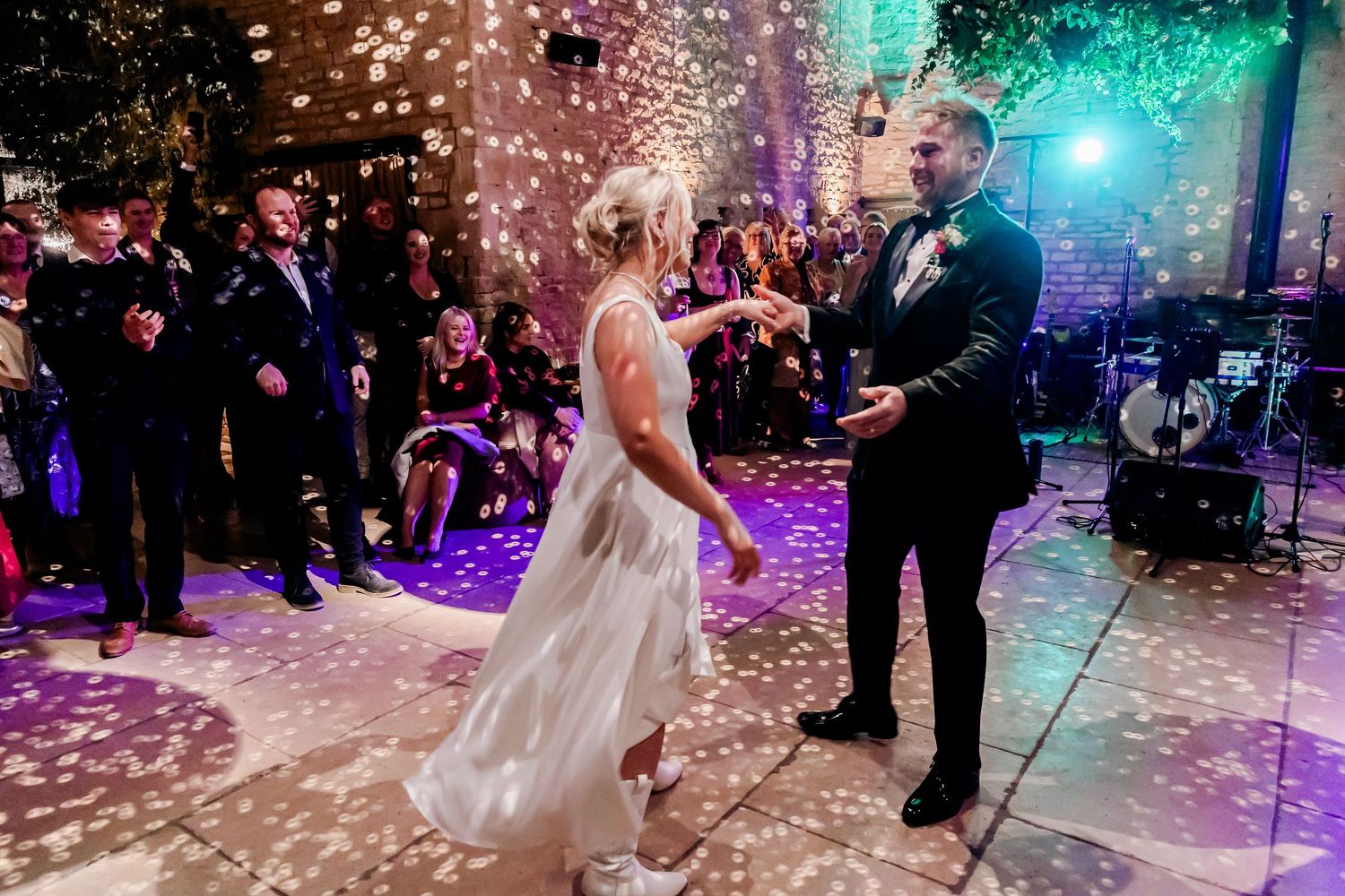 Bride and groom share their first dance surrounded by confetti and guests at elegant wedding reception.