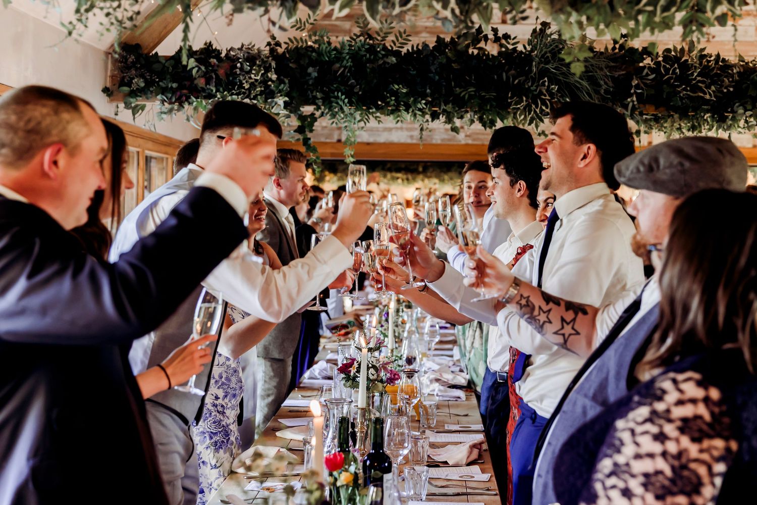 Wedding guests raising champagne glasses in a joyful toast at a decorated reception.