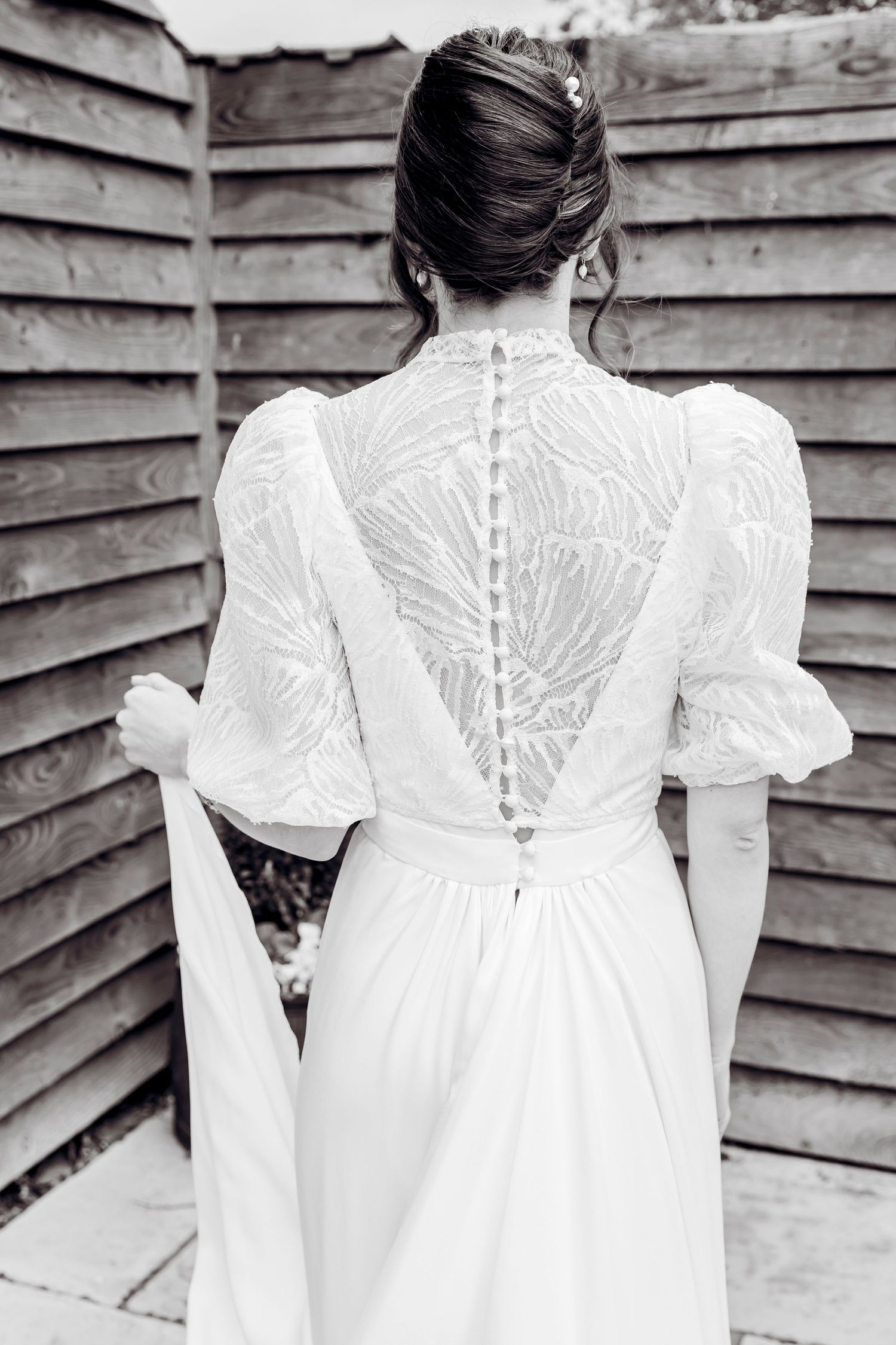 Back view of bride in white lace wedding dress with button detail and puff sleeves.