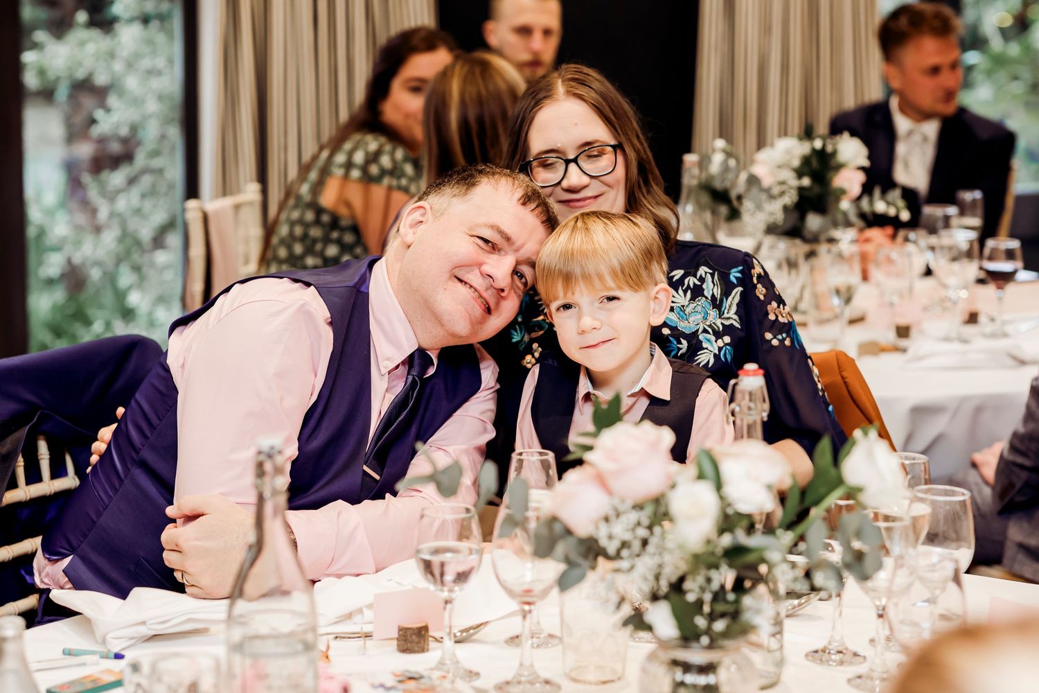 Happy family moment at a wedding reception with a man, woman, and young boy posing together.