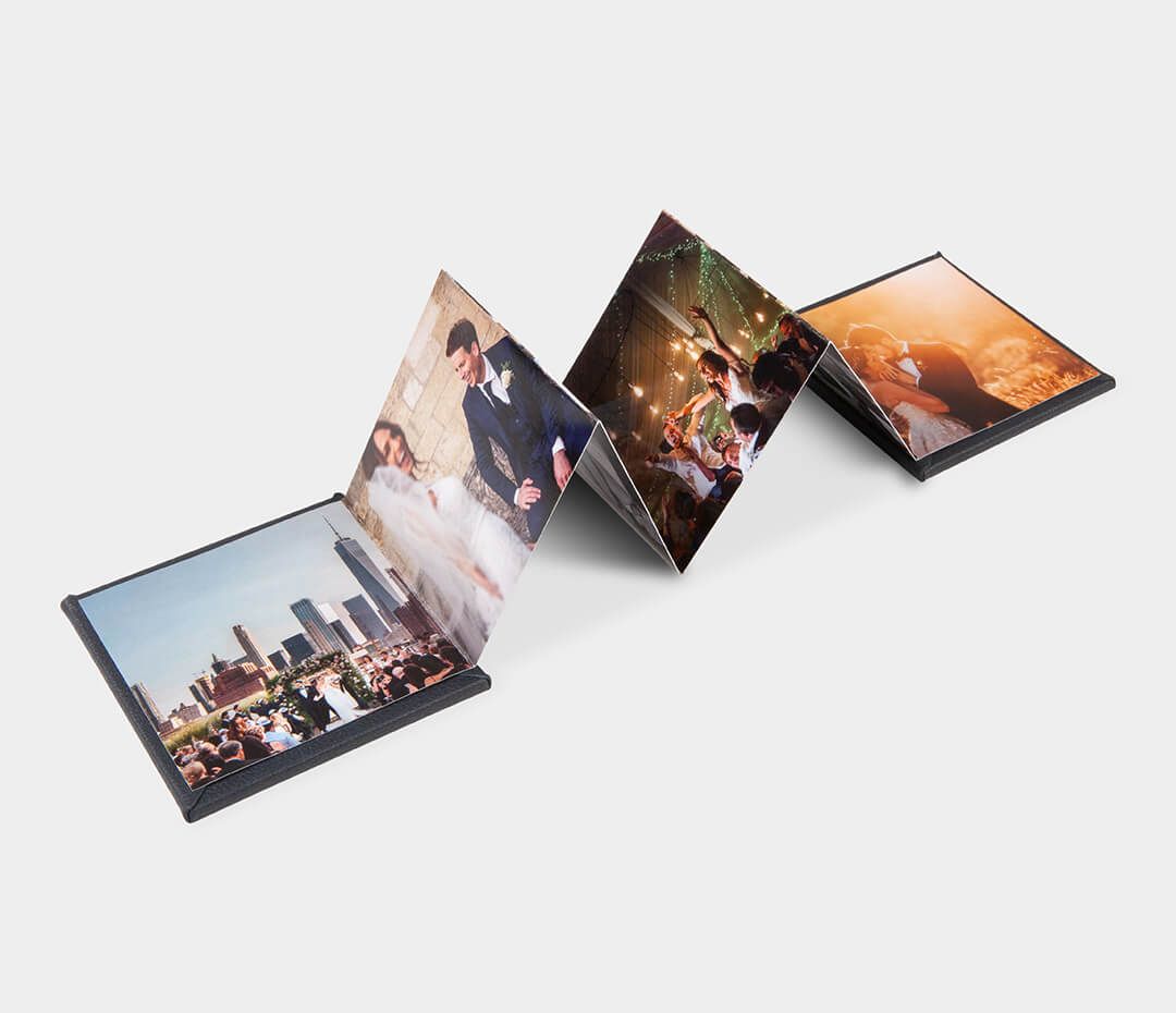 Accordion-style wedding photo book fanned open displaying four colorful celebration images.
