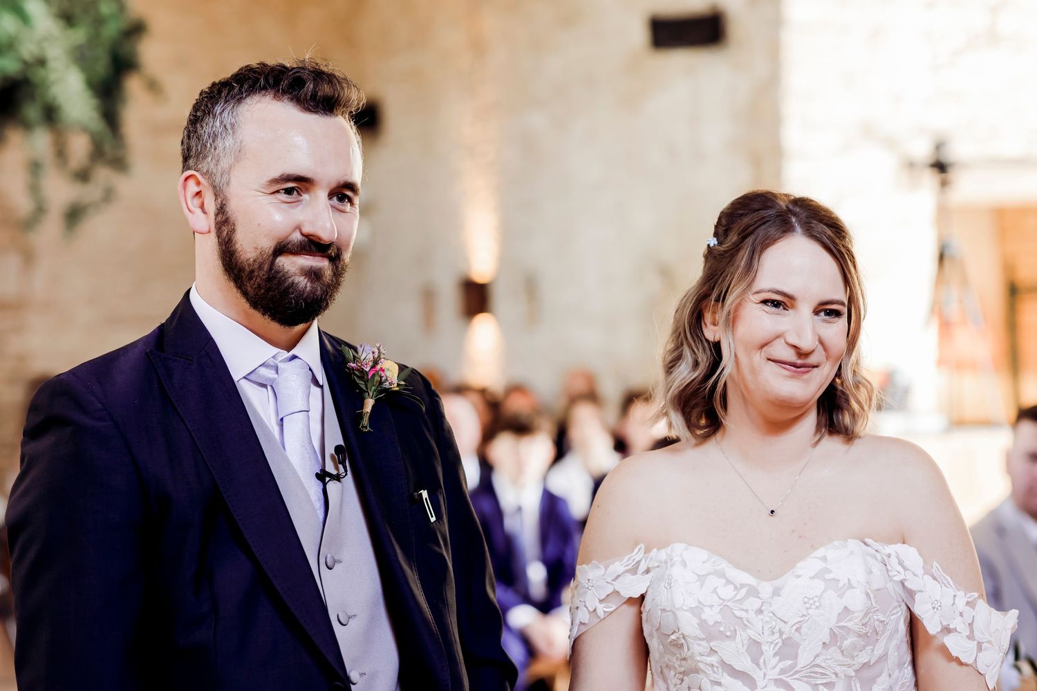 Bride and groom stand together smiling at the altar during their rustic barn wedding ceremony.