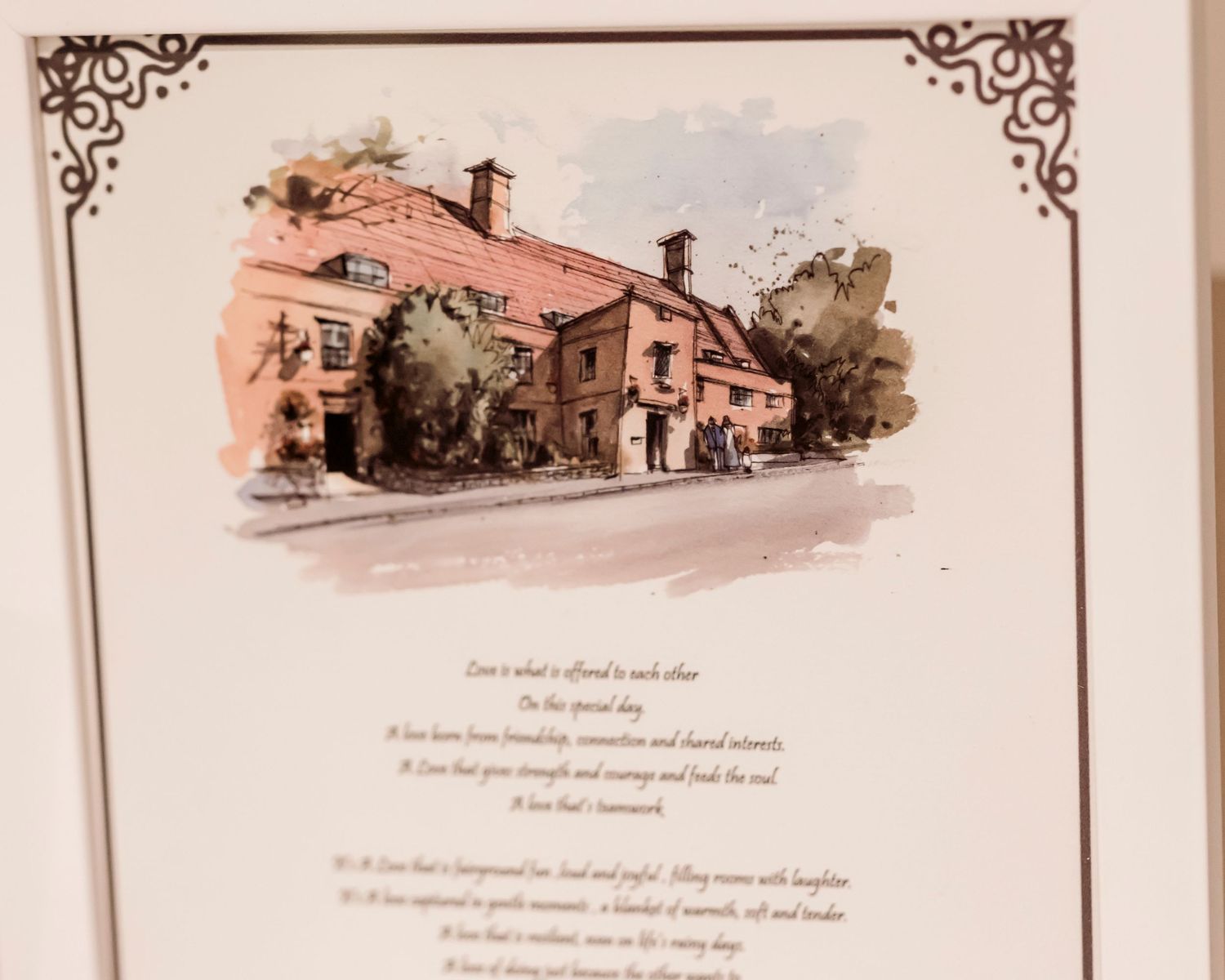Watercolor illustration of a charming countryside manor house displayed at a wedding reception.