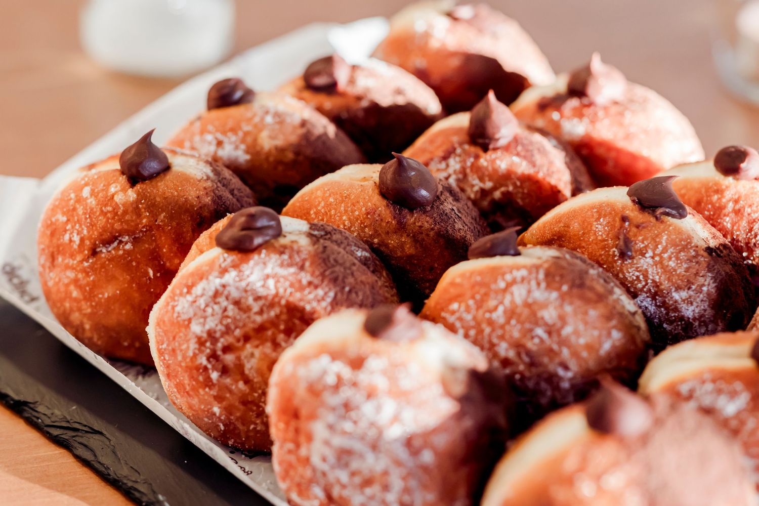Tray of powdered sugar donuts topped with chocolate chips served as a wedding dessert treat.