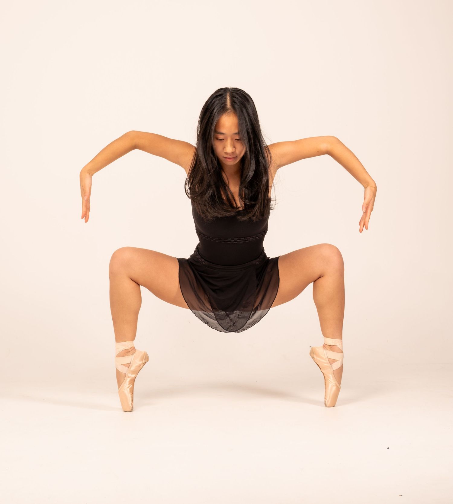 A dancer in black performs a series of graceful movements against a white backdrop.