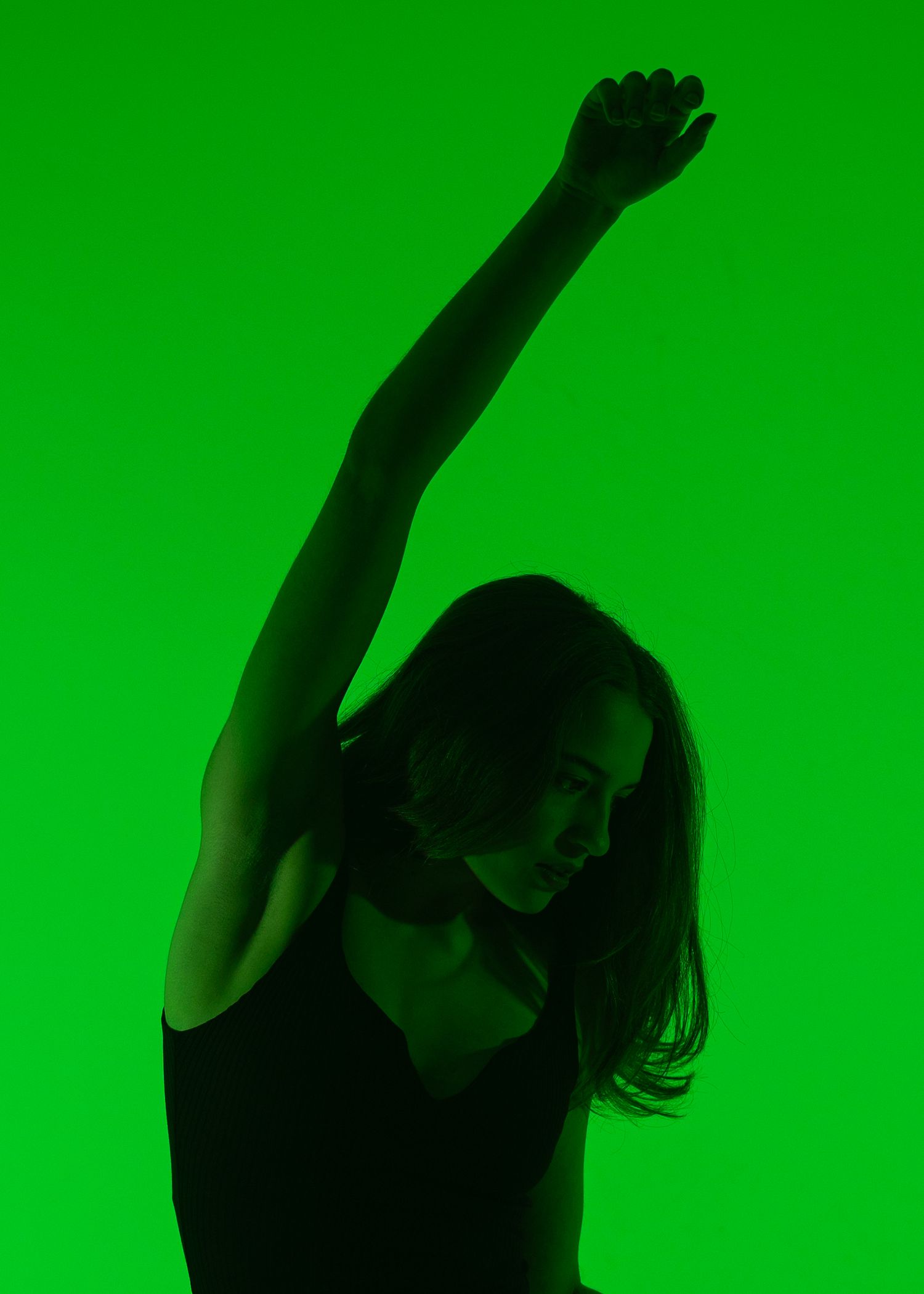 Silhouette of a woman dancing with arm raised against a vibrant green background.