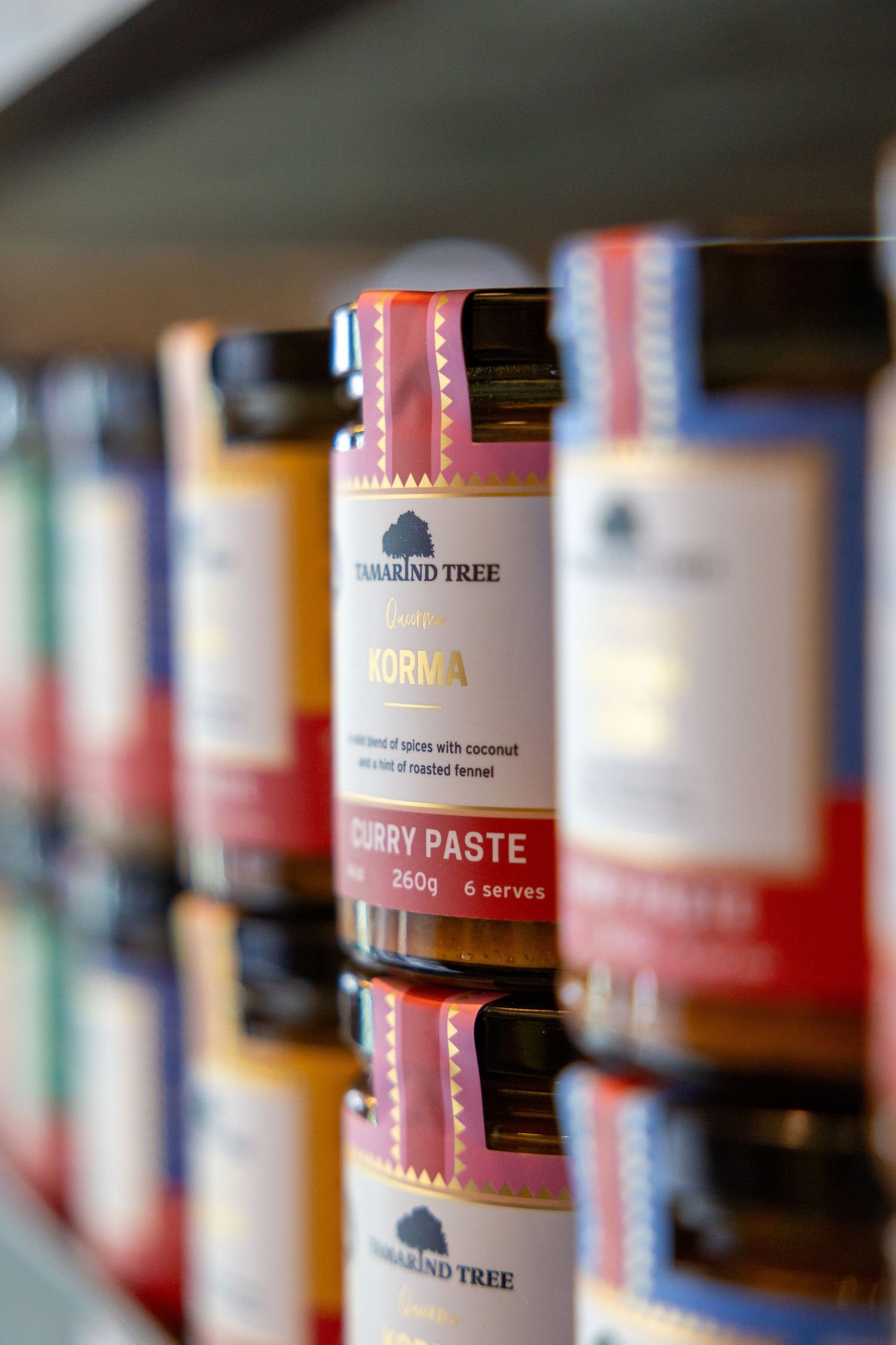 Tamarind Tree Korma curry paste jars on a shelf, 260g, 6 serves, with colorful labels.