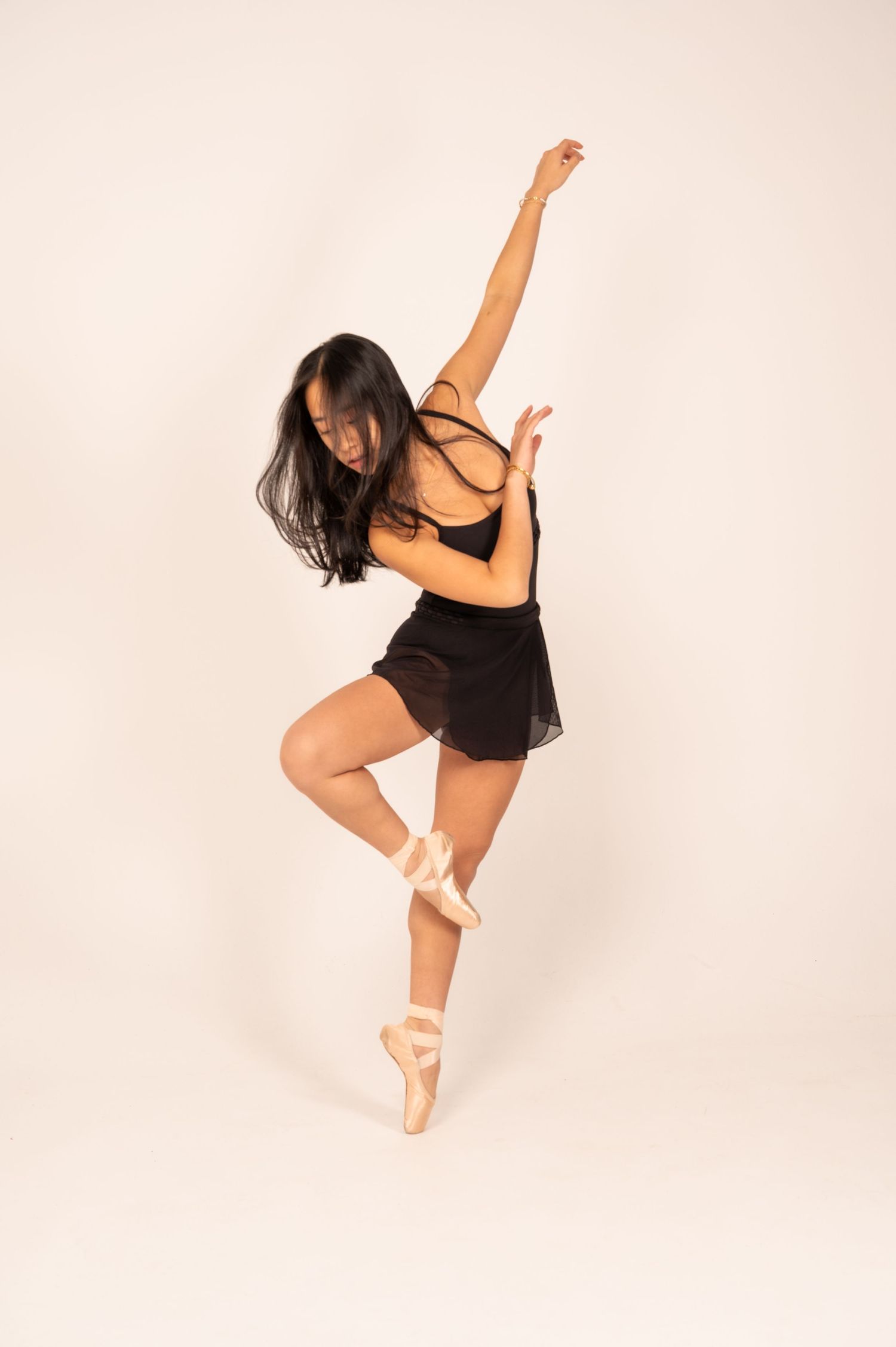 Contemporary dancer in black attire strikes dynamic poses during studio photoshoot.
