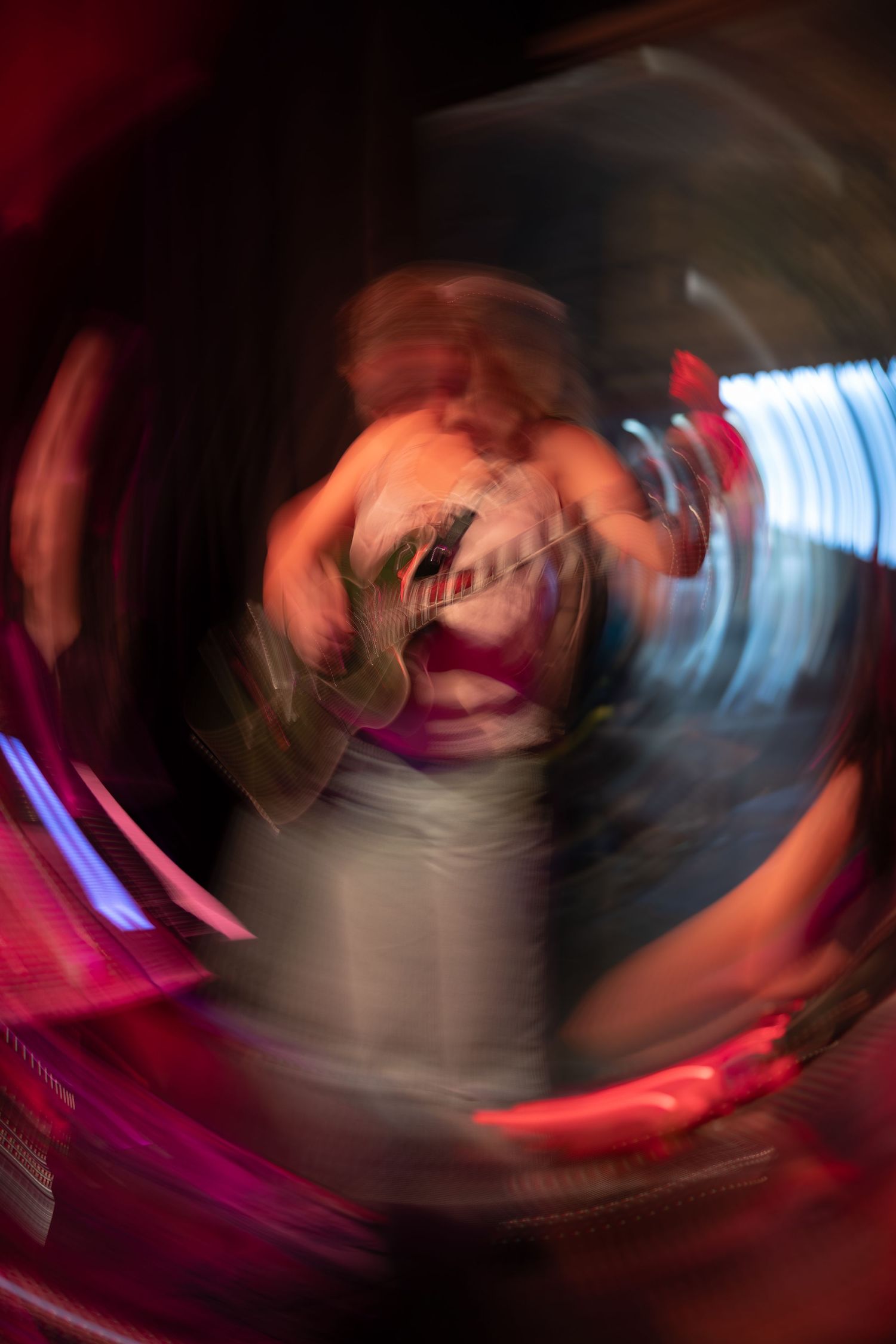 Abstract motion blur photograph with swirling red and blue lights creating a circular vortex effect in dark setting.