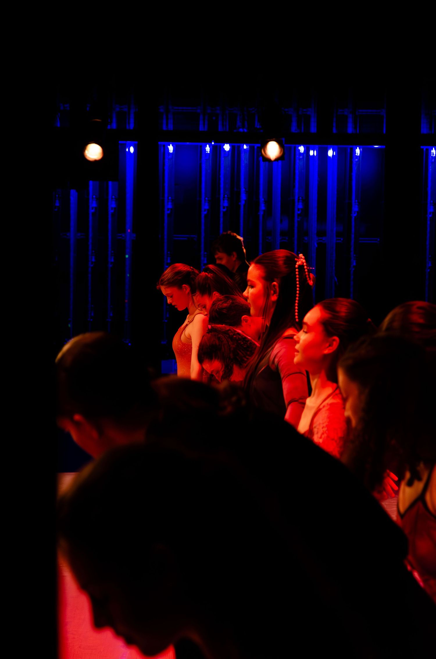 Crowd of people illuminated by blue and red stage lights at a live performance event.