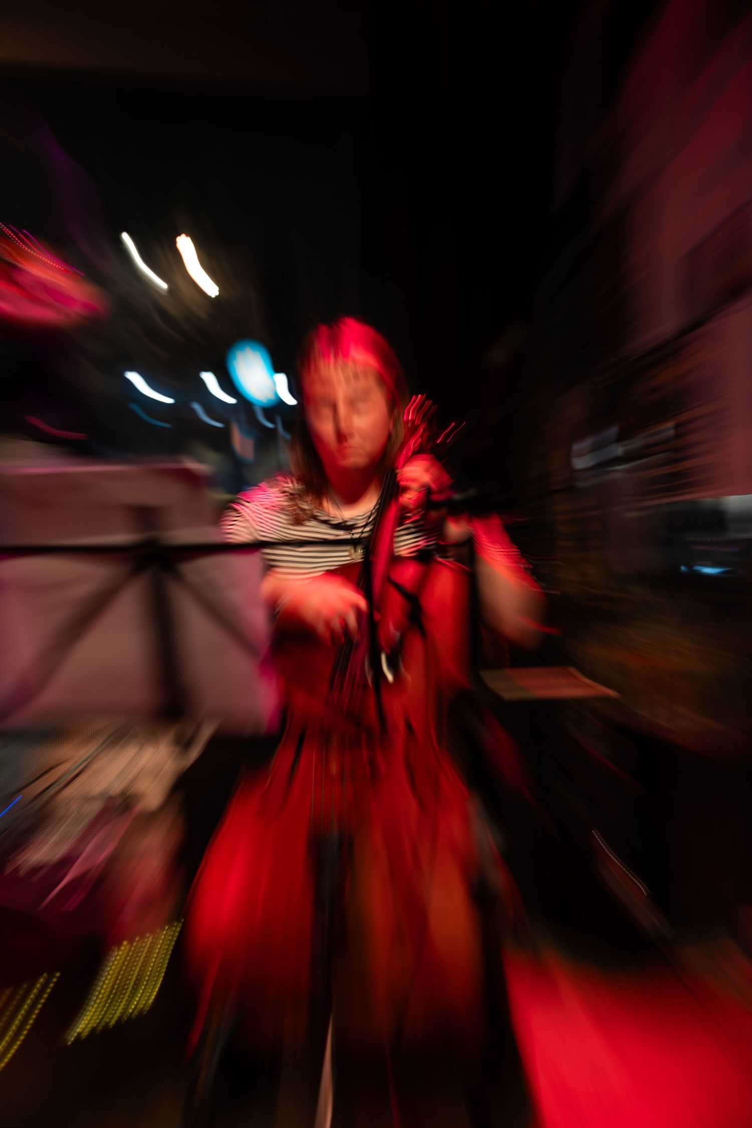 Abstract motion blur photography with red lighting creates dynamic streaks and patterns in a dark performance space.