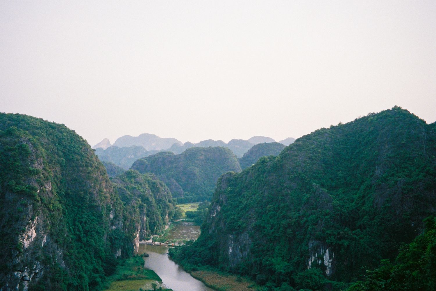 Scenic mountain valley with winding river cutting through dramatic limestone cliffs and forested peaks.