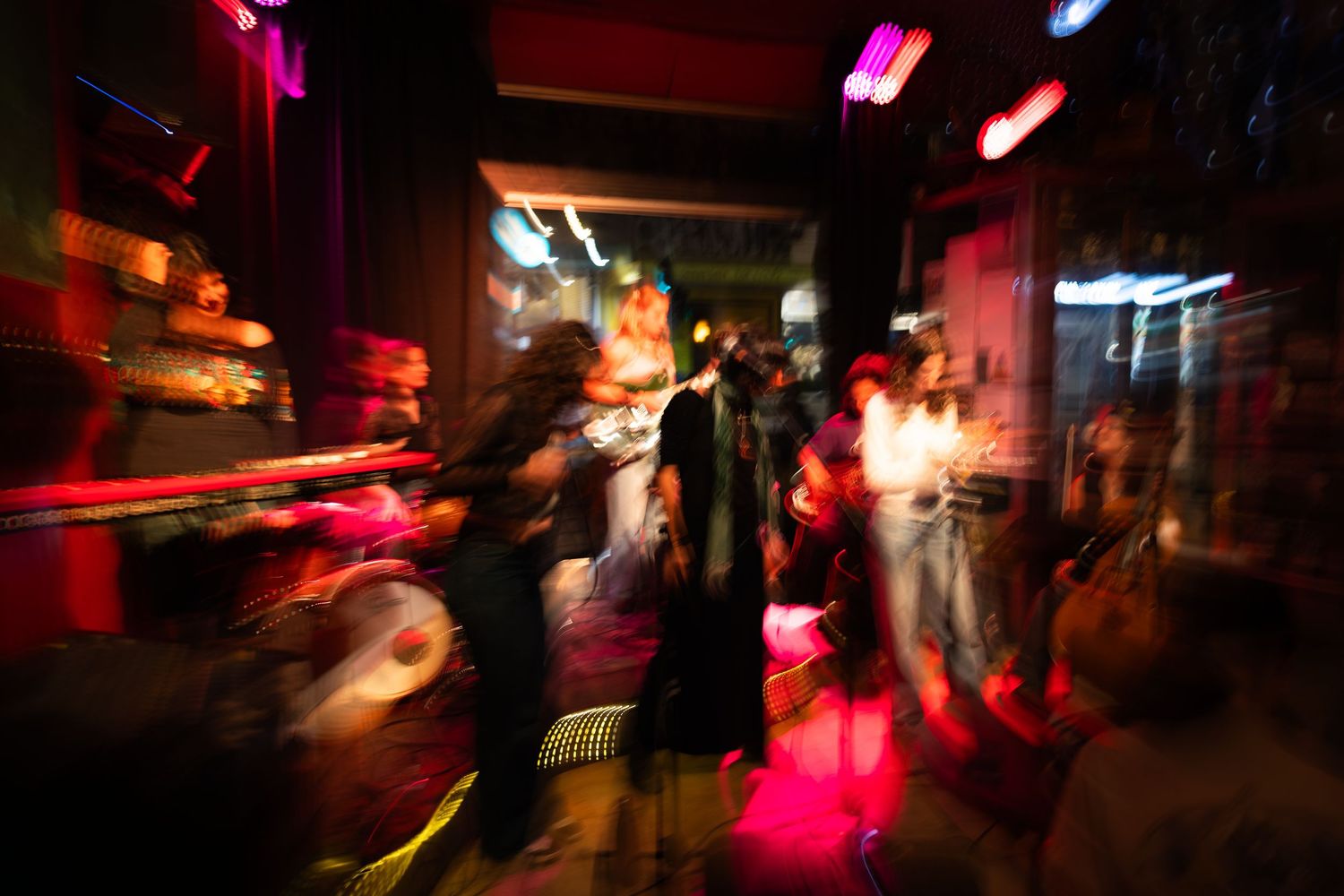 Motion-blurred nightclub scene with vibrant pink and red lights creating an energetic dance floor atmosphere.